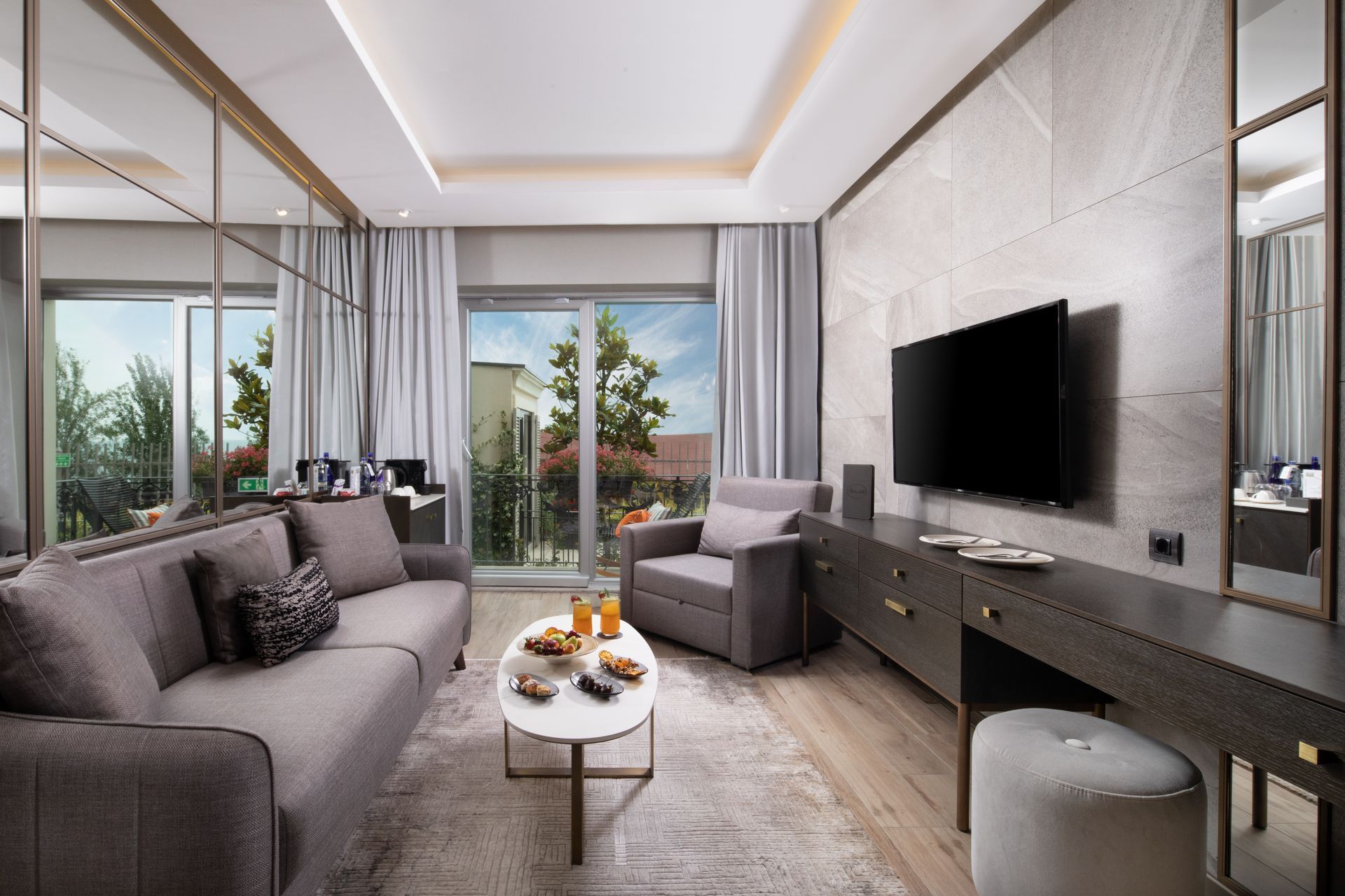 Modern living room with gray sofa, TV, coffee table, and sliding glass doors to a balcony.