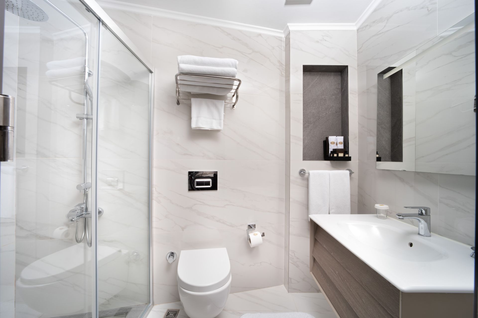 Modern white bathroom with shower, toilet, sink, and mirrored vanity | Mula Hotel
