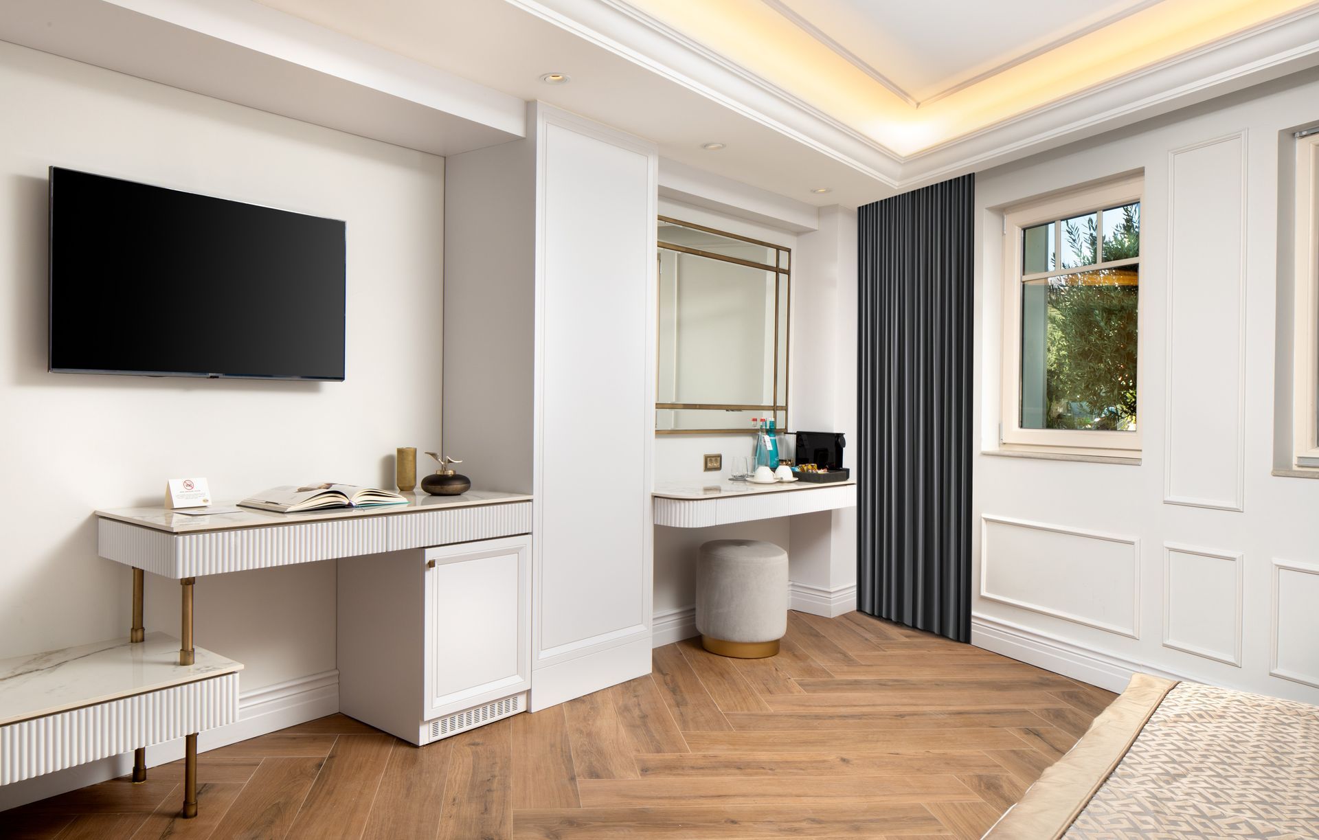 Modern bedroom with wall-mounted TV, desk, window, and white built-in cabinets