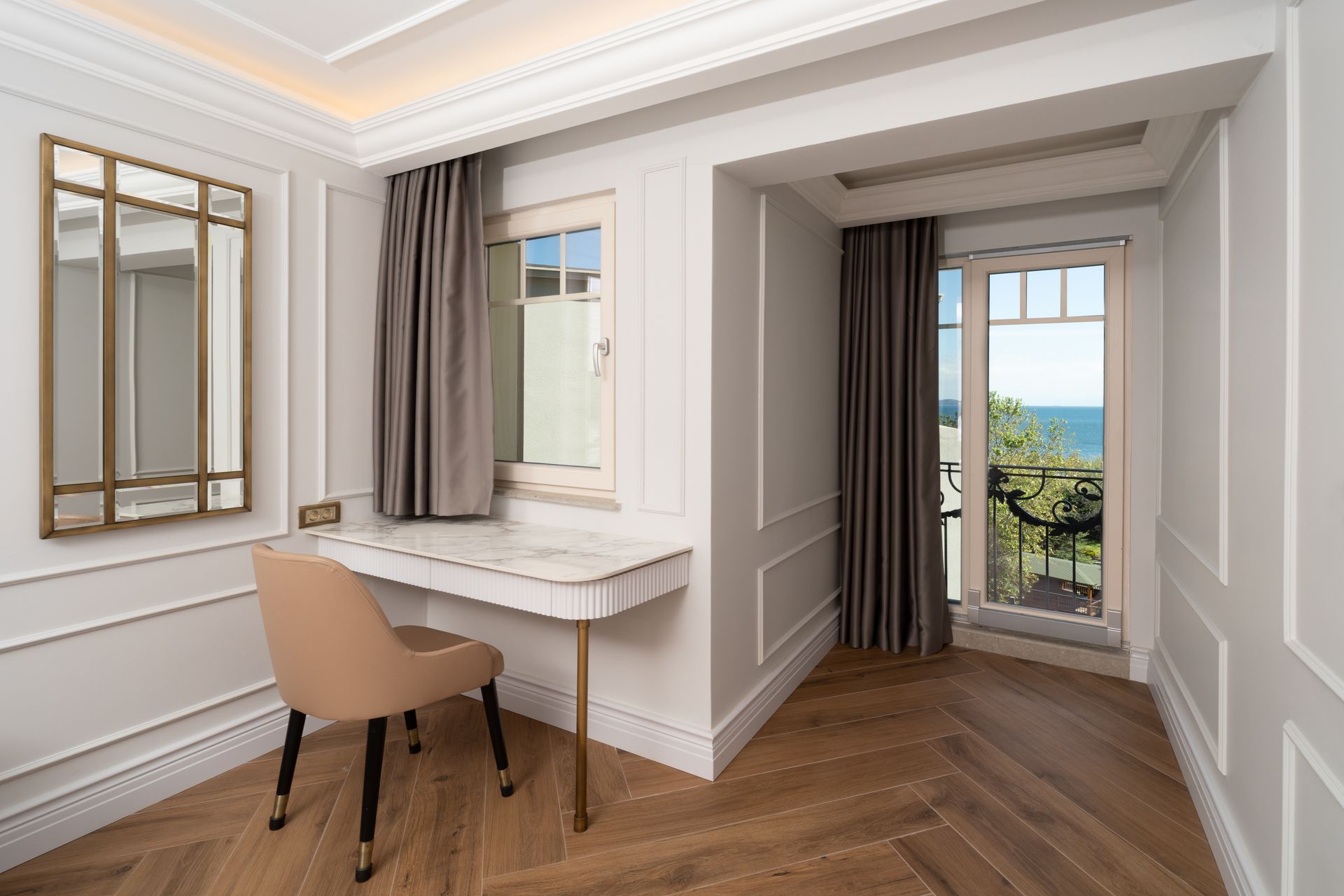 Bright bedroom nook with a desk, chair, mirrors, and an ocean view through the balcony door
