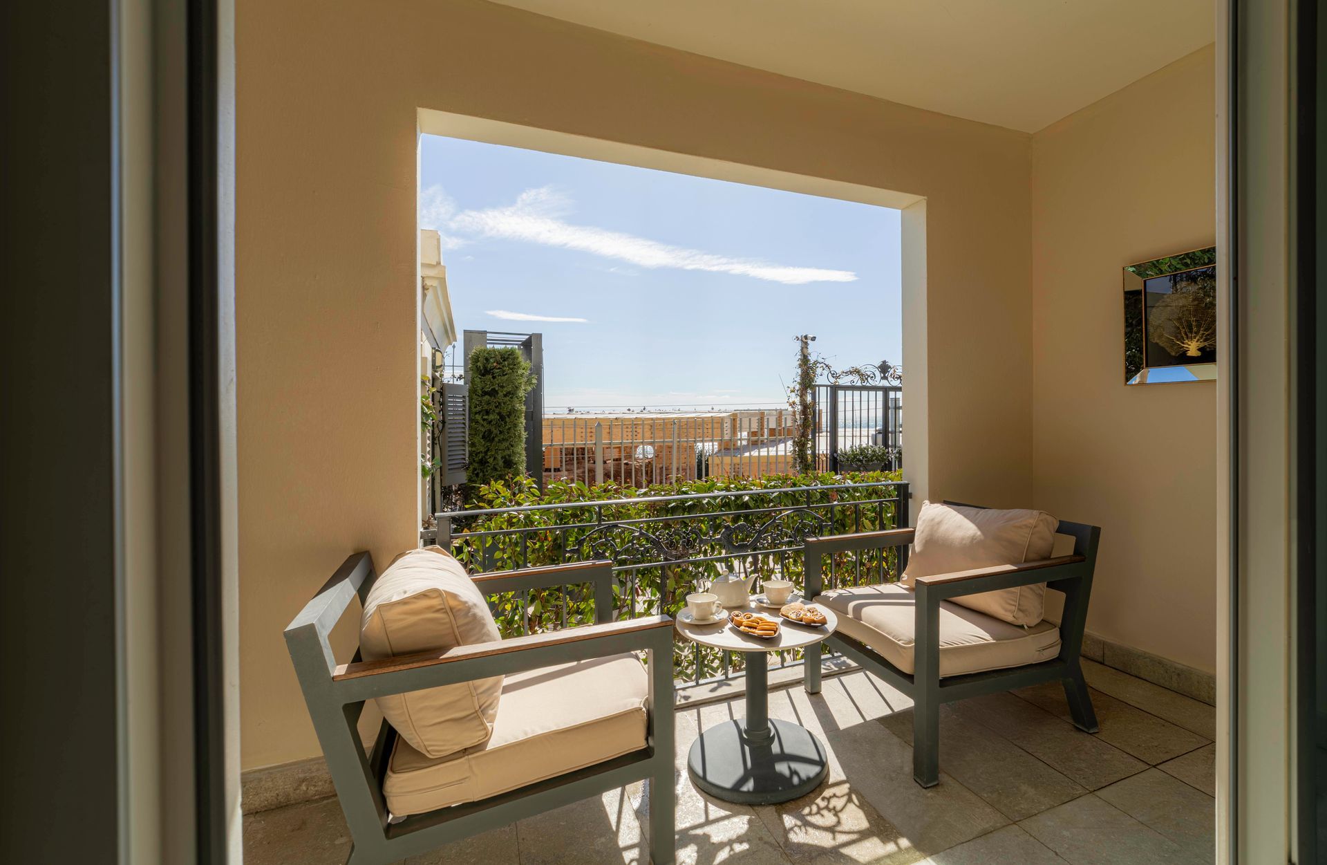 Patio seating by a sunlit window overlooking a cityscape and greenery