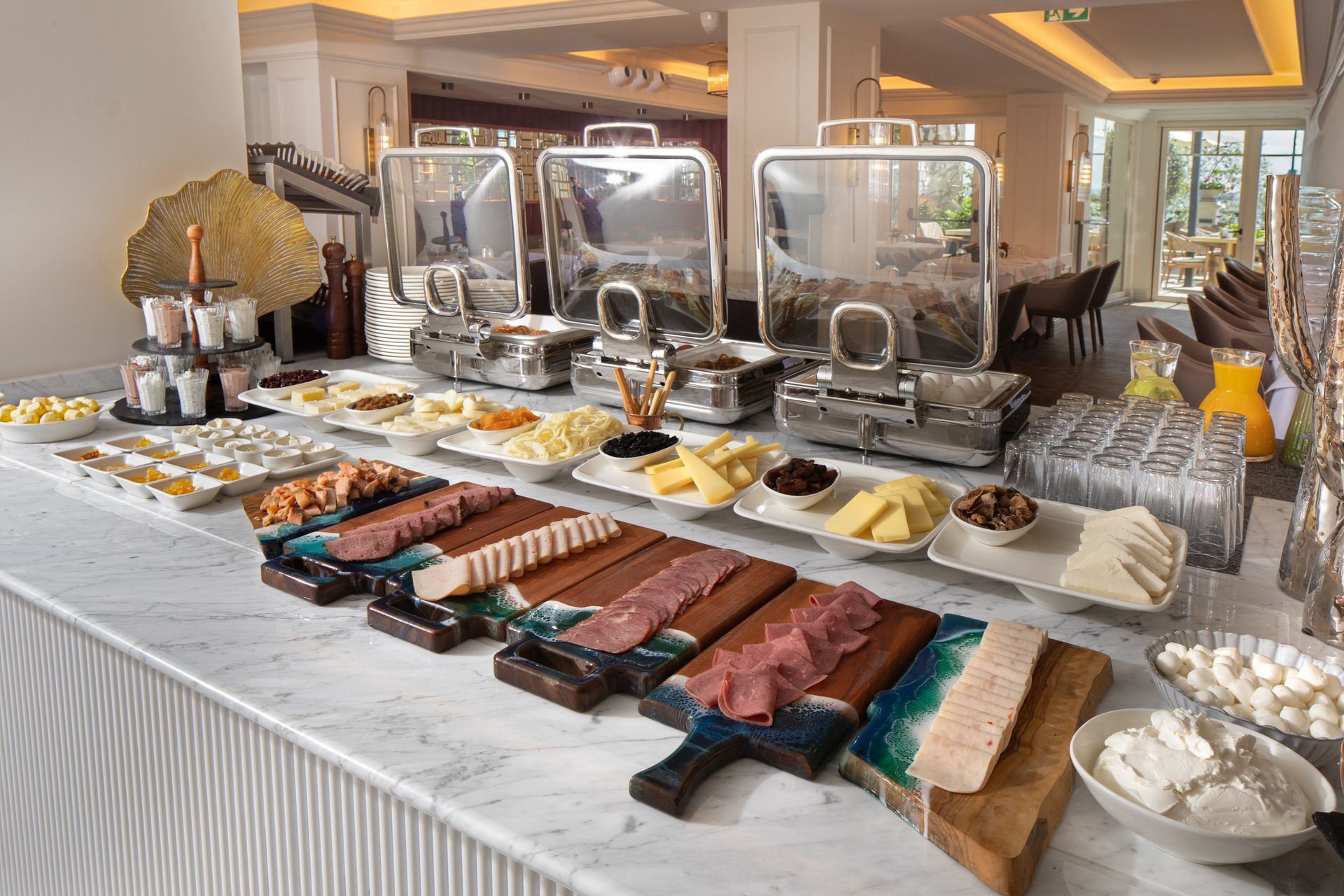 Elegant buffet table with assorted pastries, fruit, and chafing dishes in a bright dining room
