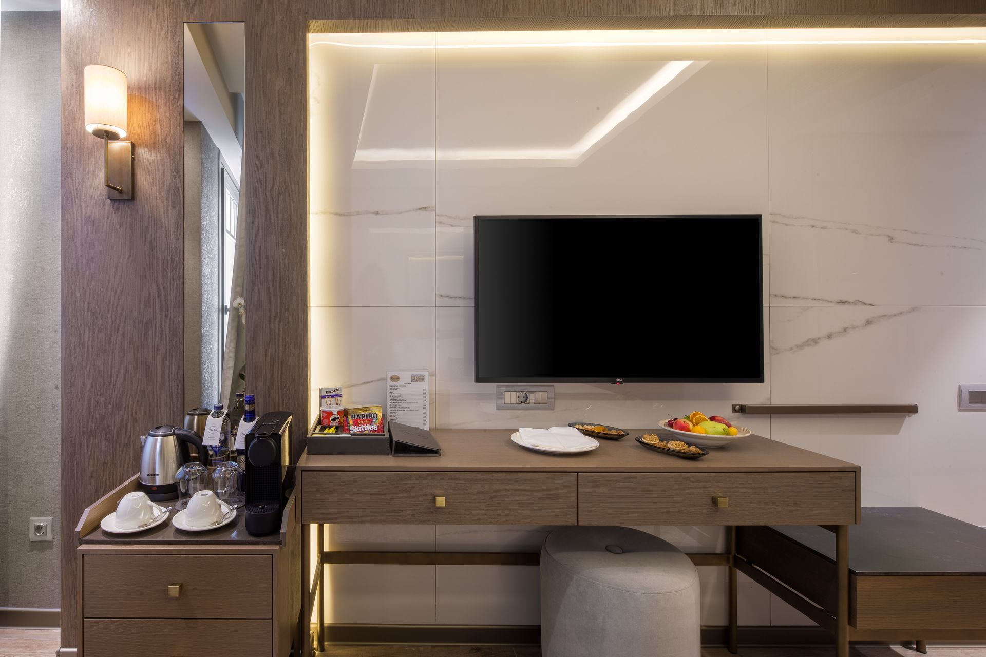 Hotel room desk with TV, coffee set, and snacks in a modern interior