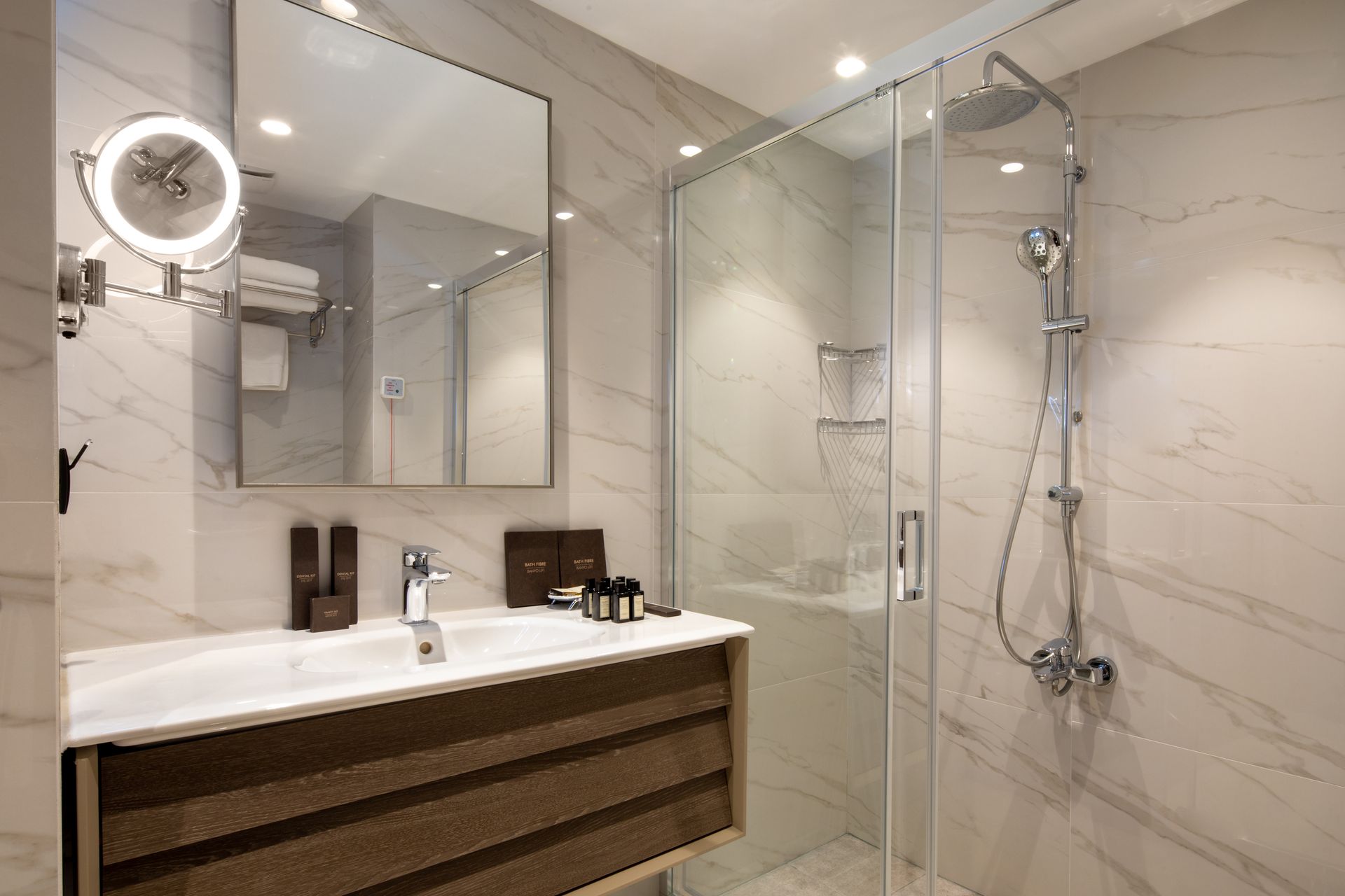 Modern bathroom with a glass shower, large mirror, and wood vanity with sink.