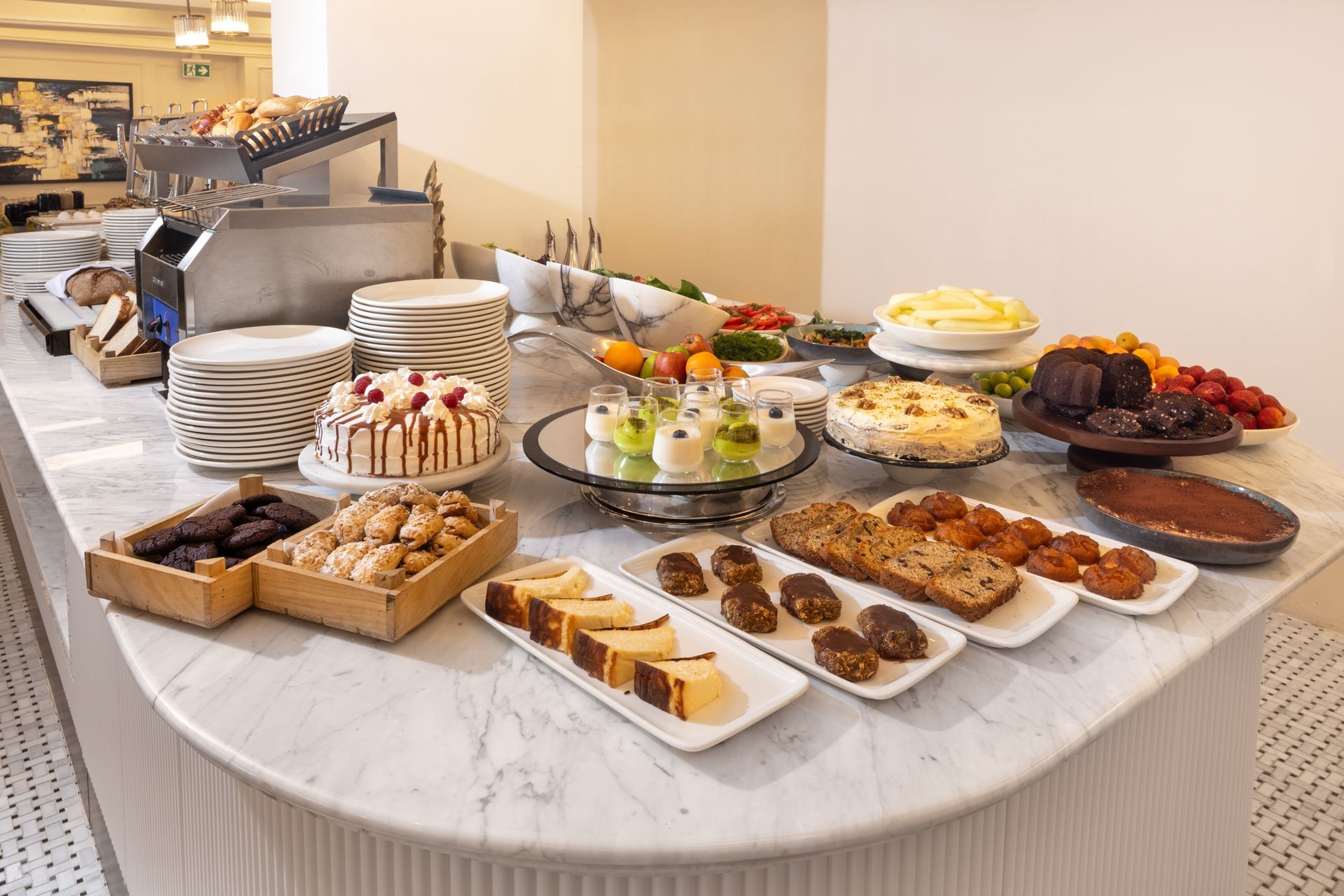 Buffet dessert table with cakes, pastries, and assorted sweets on a white tablecloth