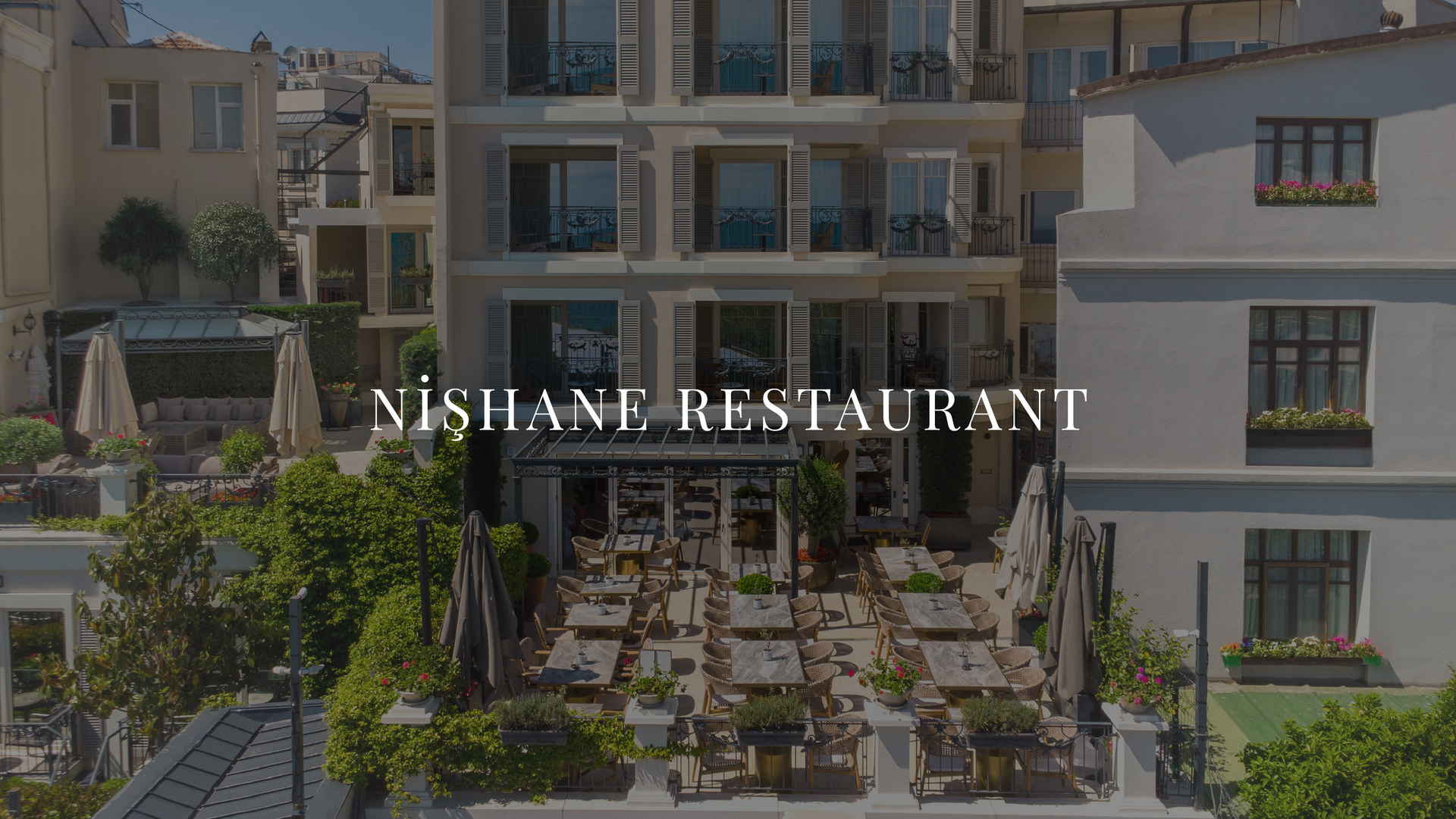 Outdoor dining courtyard at VISHAN RESTAURANT between buildings, with tables and greenery under a sunny sky