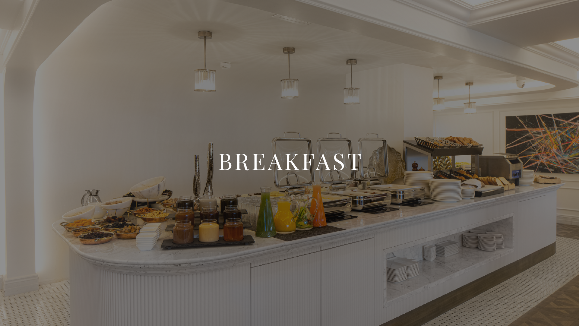 Hotel breakfast buffet with pastries, fruit, and drinks on a long white counter