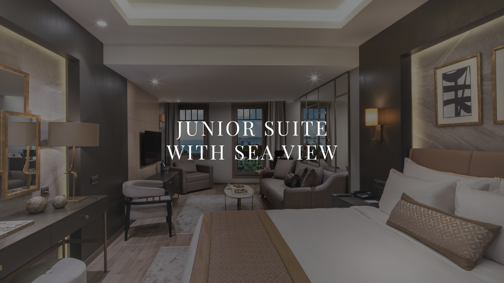 Luxury hotel suite with king bed and sea view, featuring neutral tones and large windows
