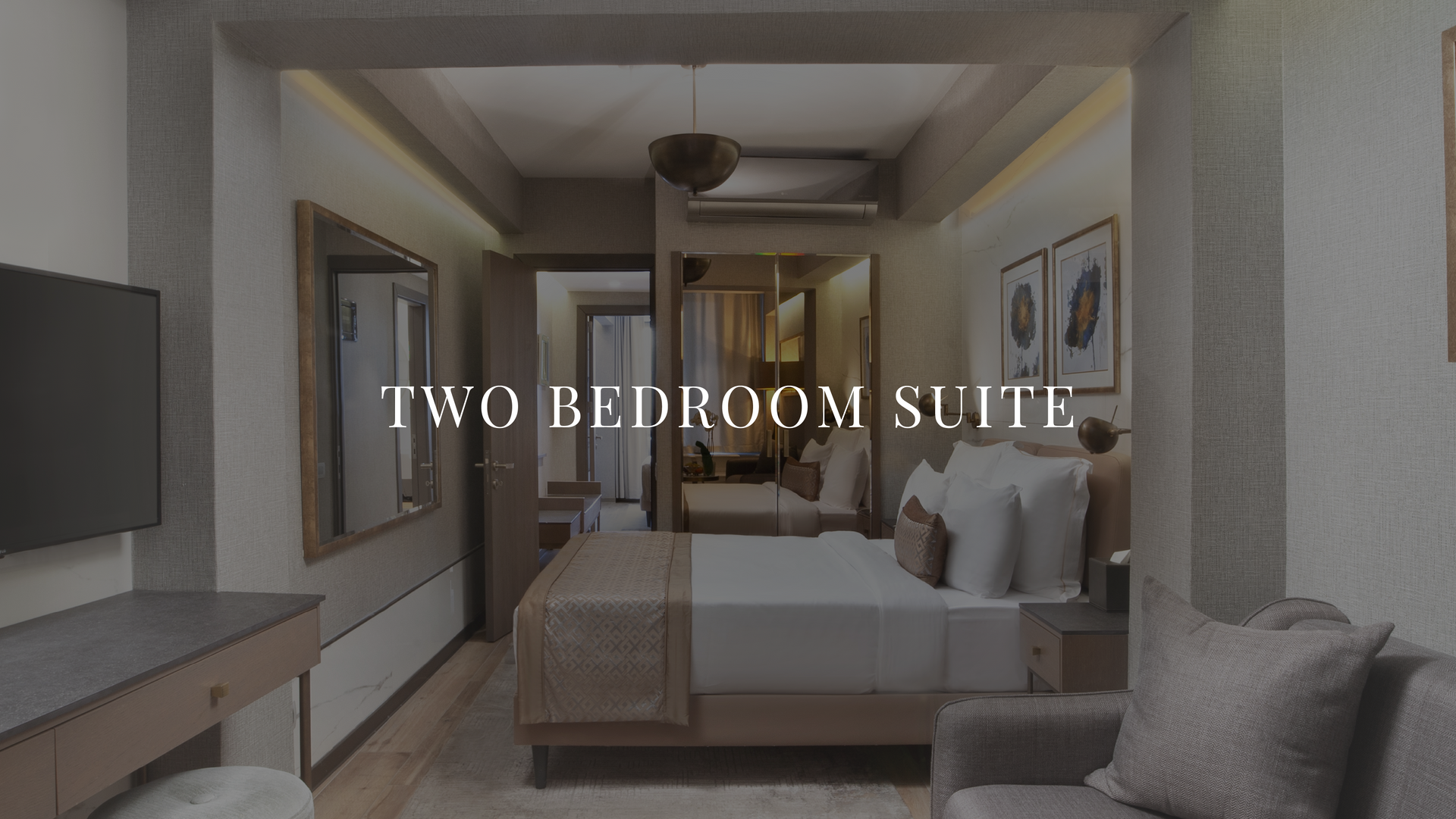 Two-bedroom suite with a bed, sofa, and neutral-toned decor in a bright hotel room.