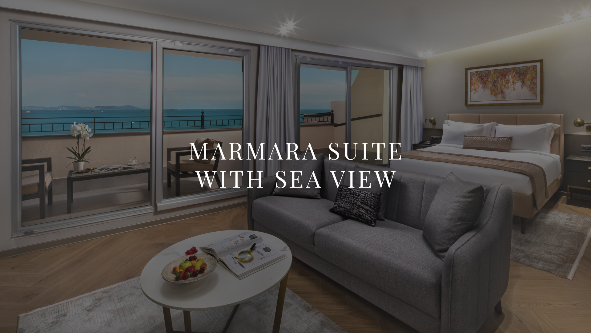 Luxury hotel room with sea view, featuring a bed, sofa, and balcony overlooking the water