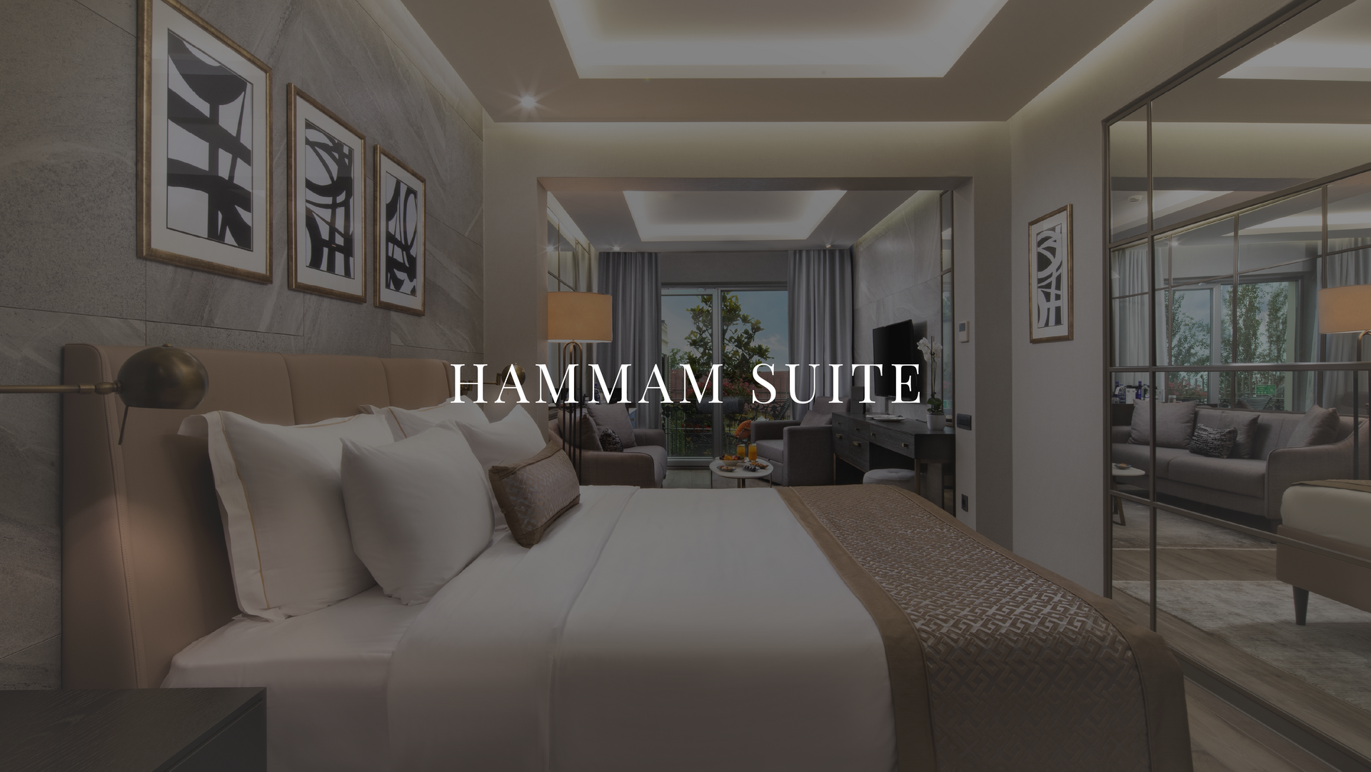 Luxury bedroom suite with king bed, neutral decor, and “HAMMAM SUITE” text overlay