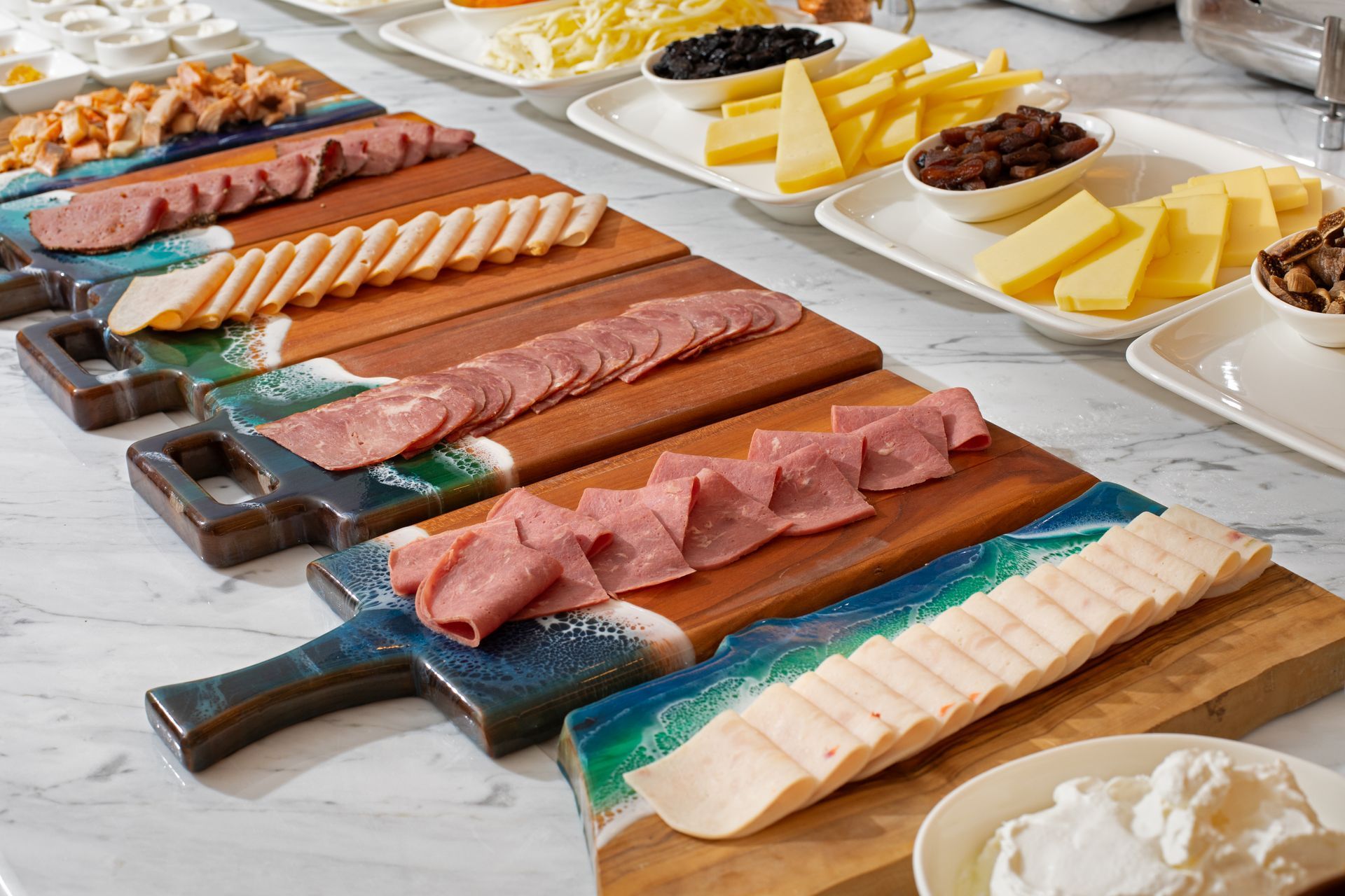 Mula Hotel | Charcuterie board with sliced meats, cheese, and sides on a buffet.