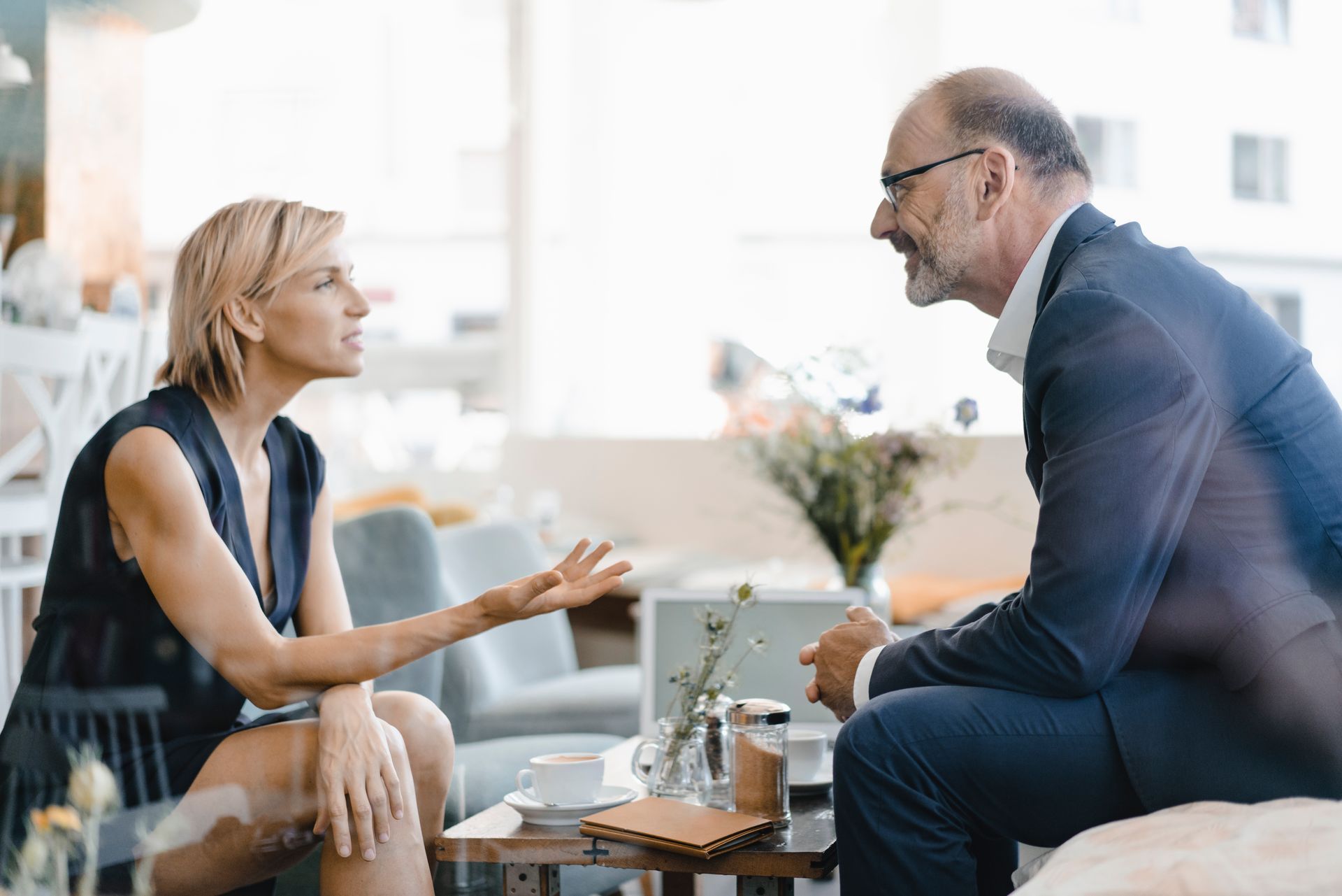 Two coworkers talking over coffee in a bright office lounge