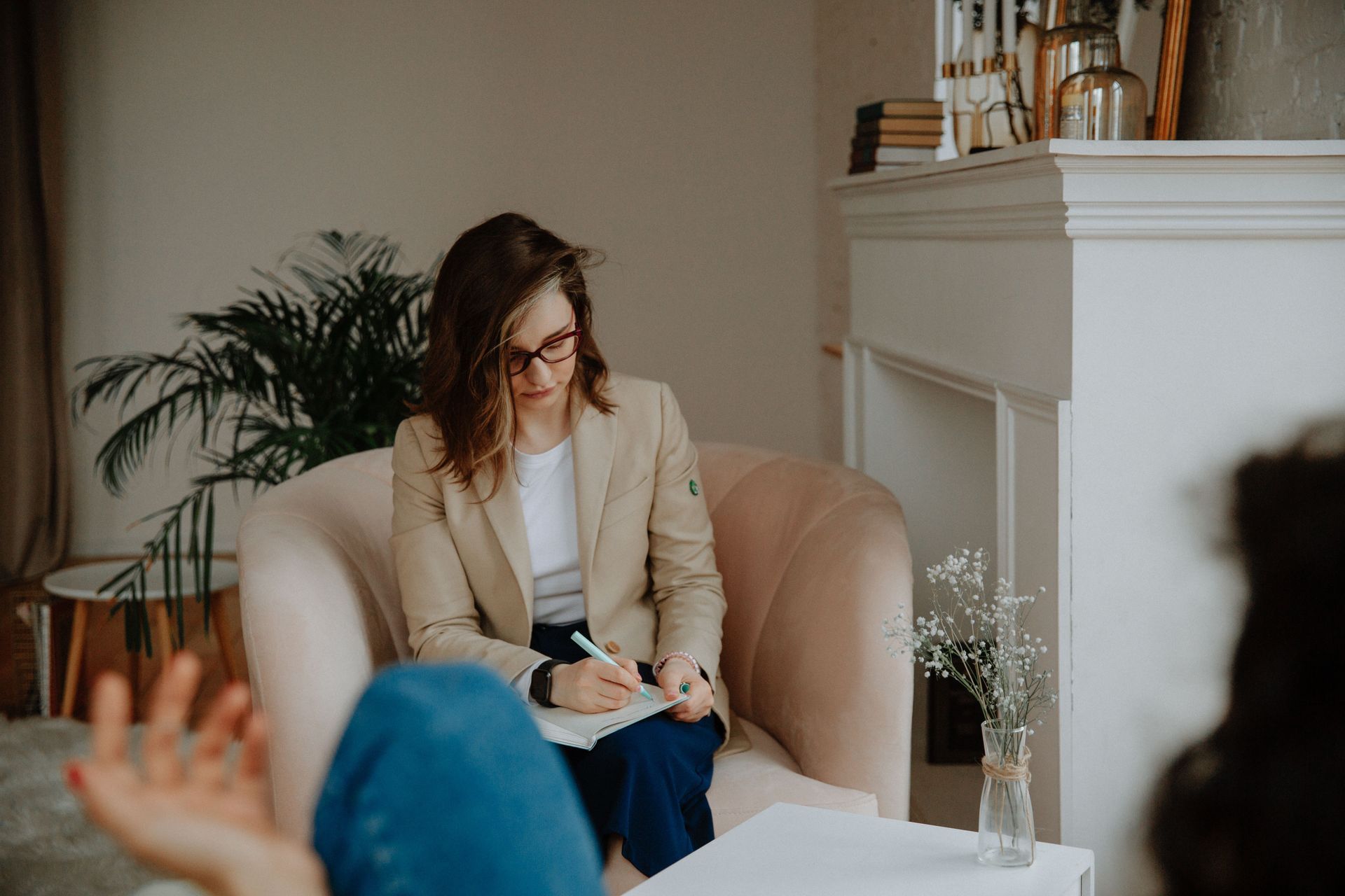 Therapist taking notes with a client in a cozy living room setting