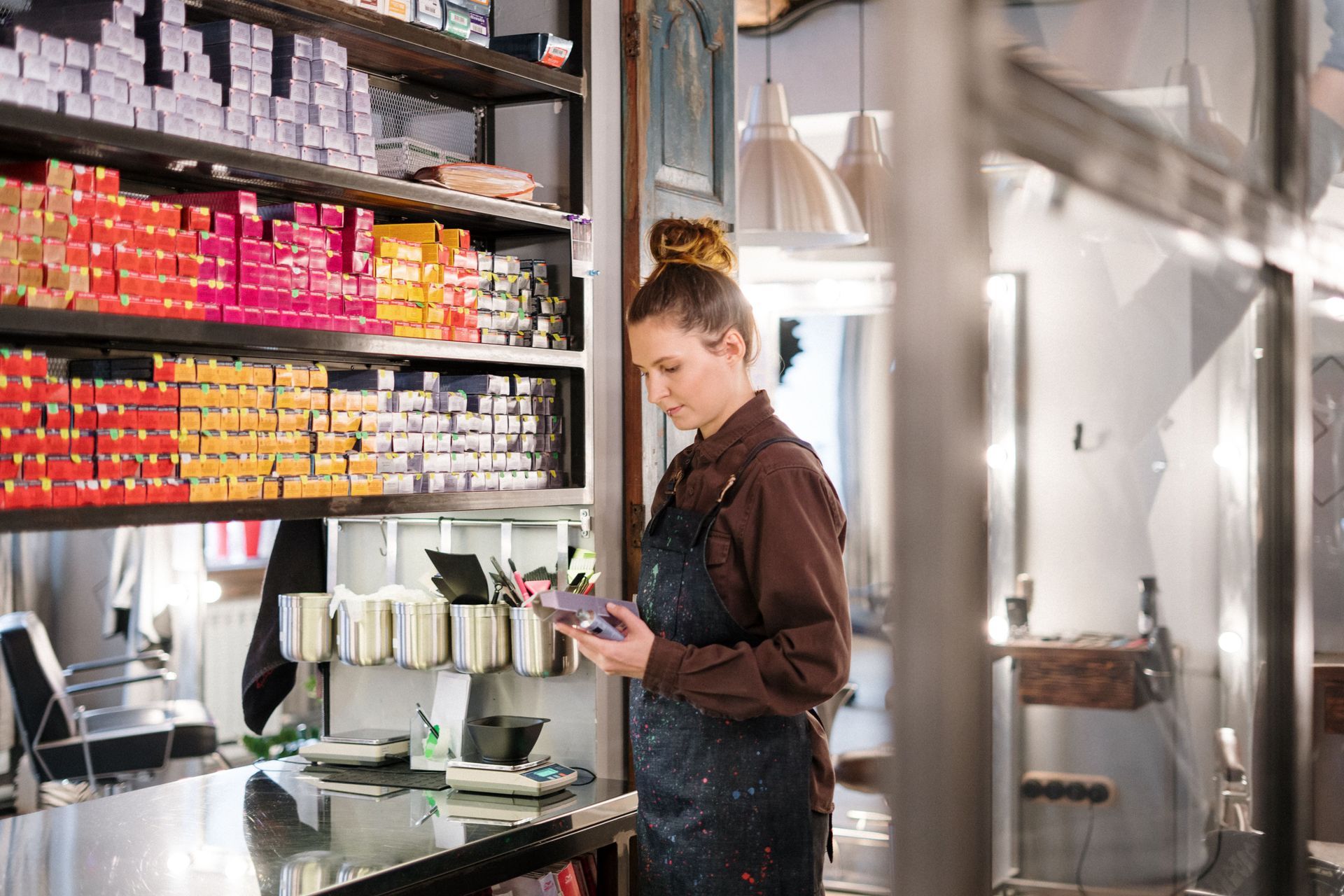Barista preparing a drink behind a cafe counter with shelves of colorful supplies behind her