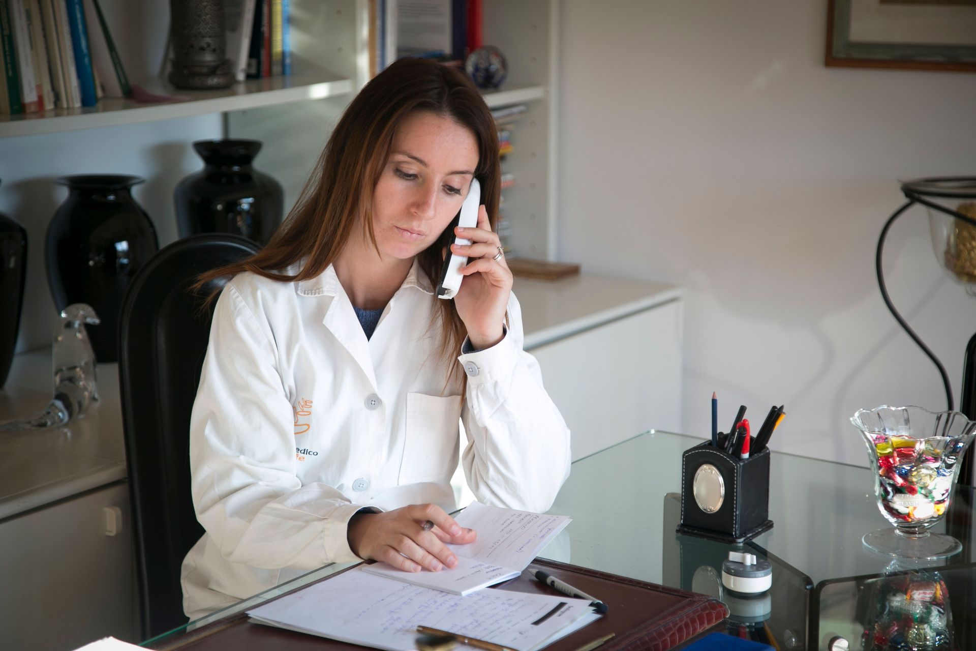 Woman on phone at a desk with paperwork in an office