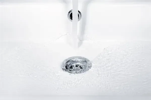 White sink with running water flowing into the drain.