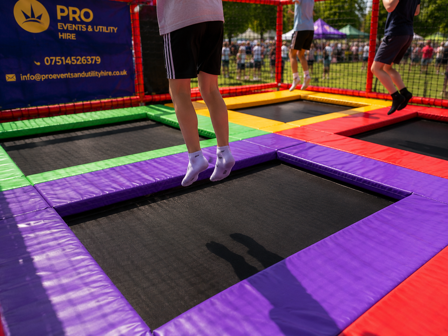 People bouncing on colorful square trampolines at an outdoor trampoline park