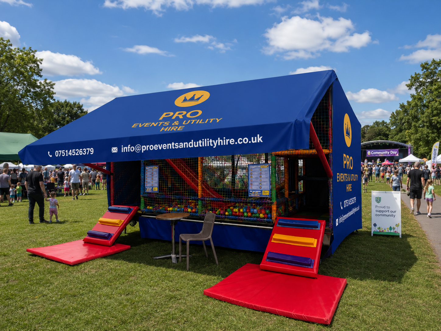Blue event tent stall with ramps and colorful sports equipment on a grassy field at an outdoor fair