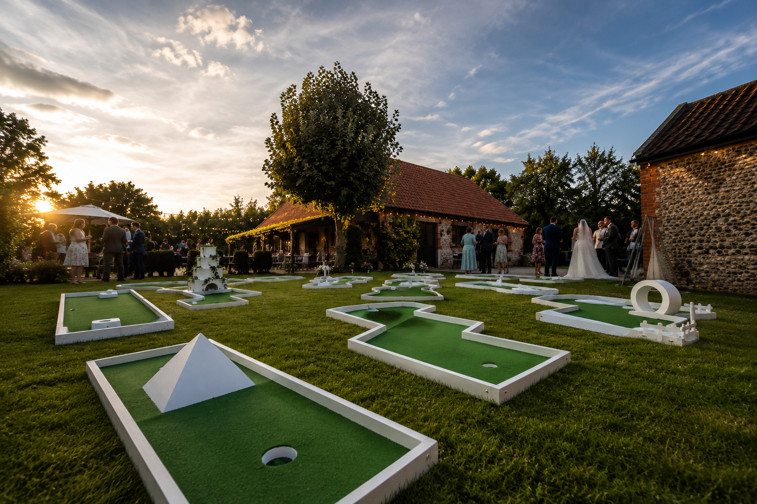 Mini-golf course at sunset with white obstacles, fountains, and a brick clubhouse in the background