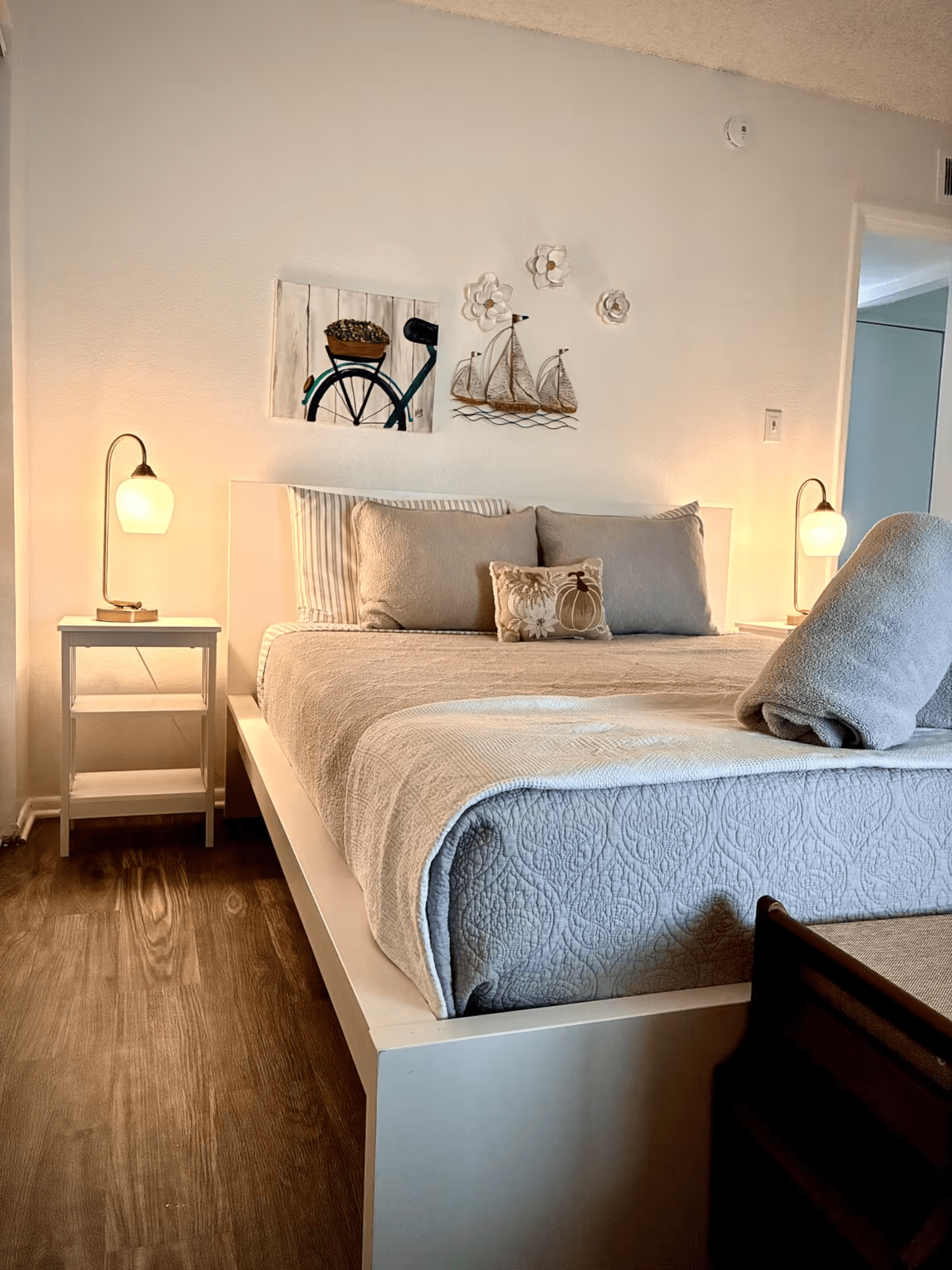 Cozy bedroom with a neatly made white bed, bedside lamps, and wall art above the headboard