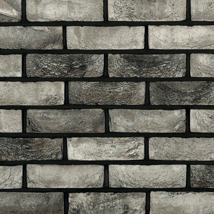 Gray and black brick wall, close-up with textured surface and dark mortar between bricks.