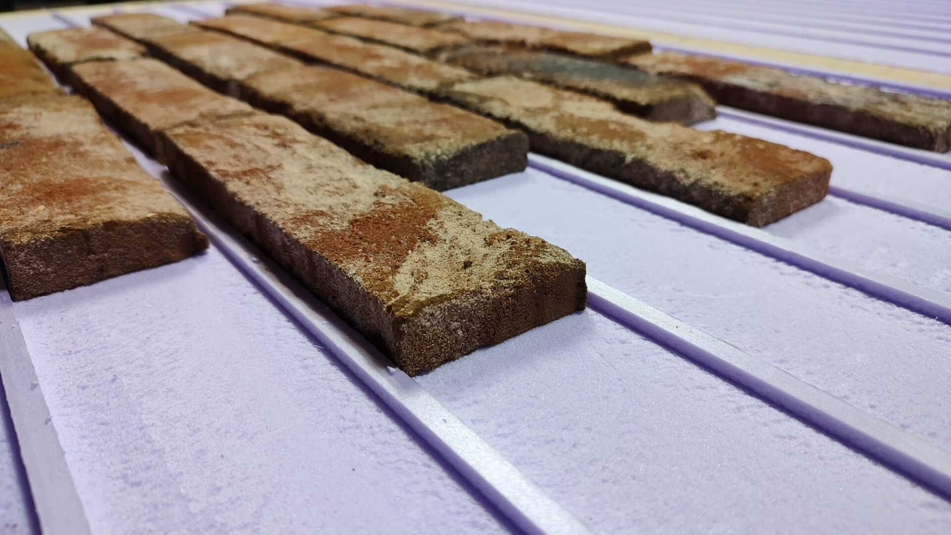 Brick-like tiles on white, ridged surface. Some tiles have tan powder. Diagonal perspective.