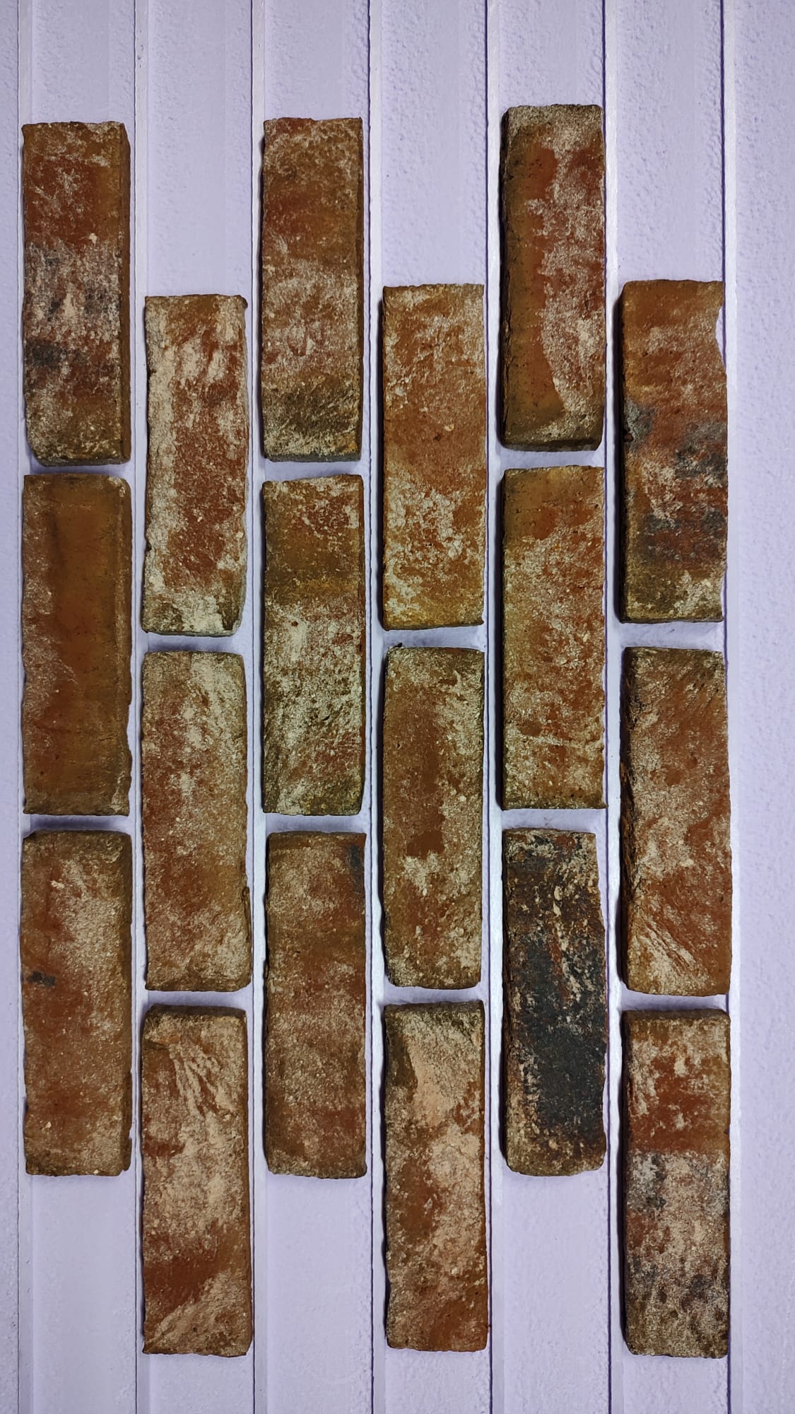 Brick tiles arranged vertically, separated by white vertical stripes. Brown, textured bricks.