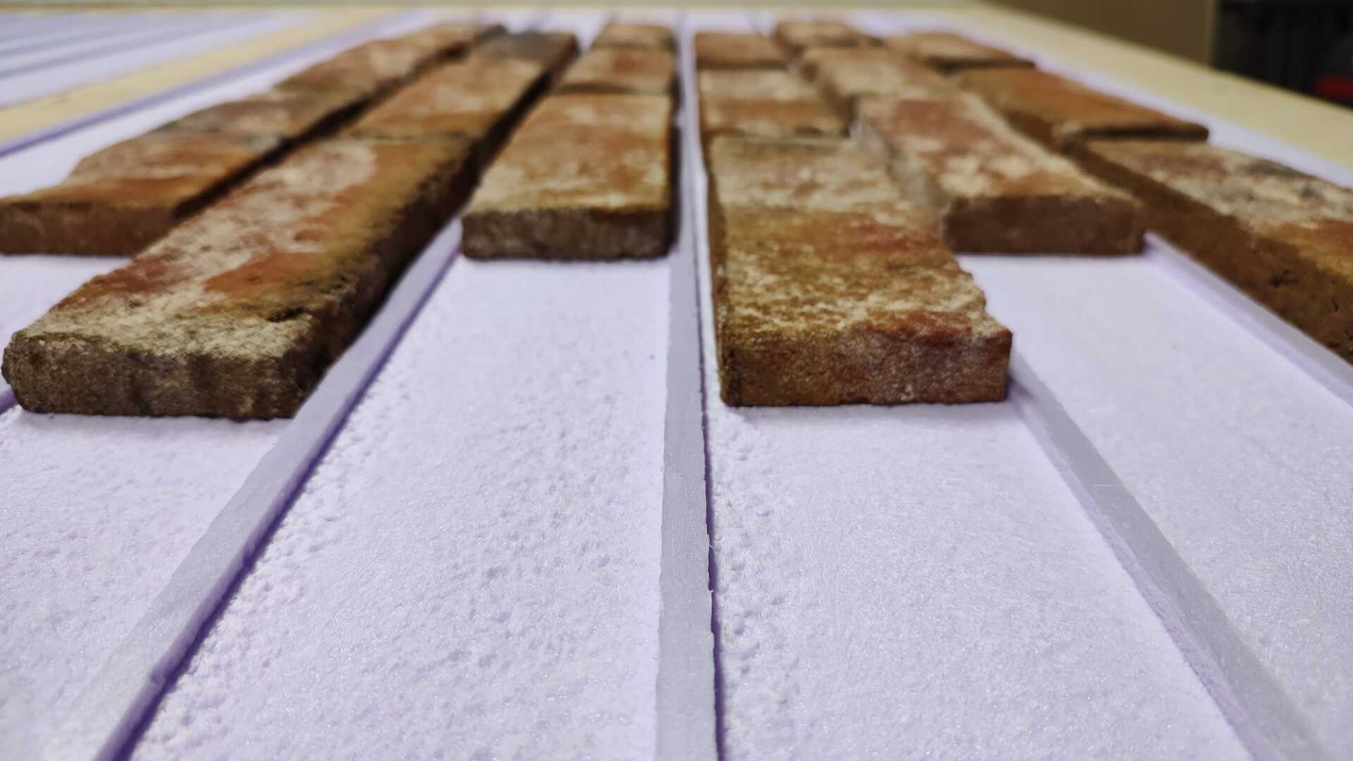 Rows of rectangular bricks on a grooved white surface.