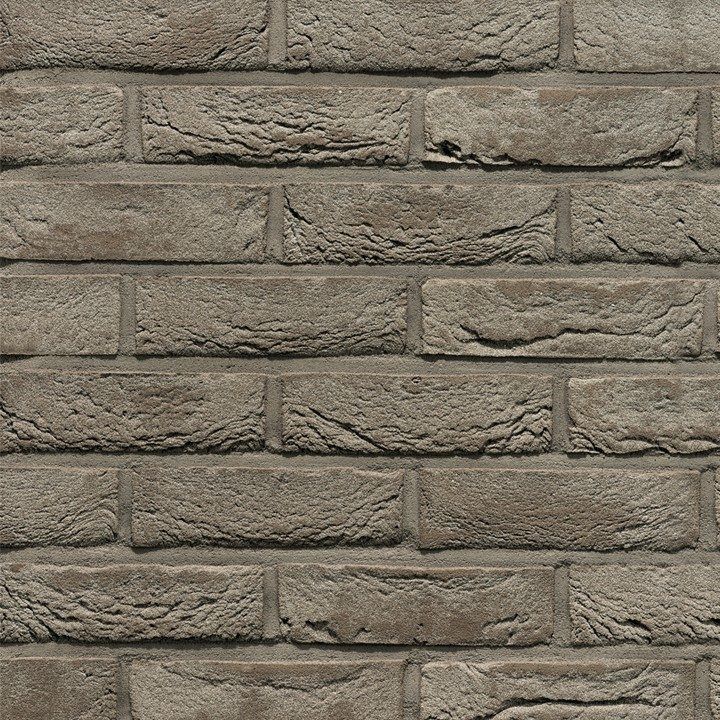 Close-up of a weathered, grey brick wall with rough texture and mortar lines.