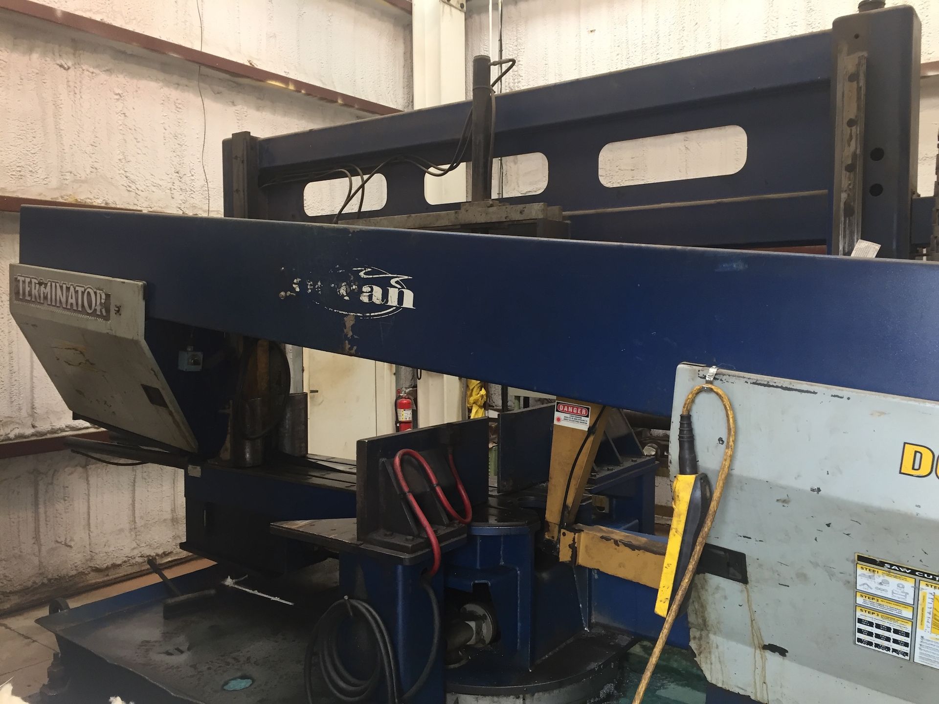 Blue and gray industrial band saw machine in a workshop.