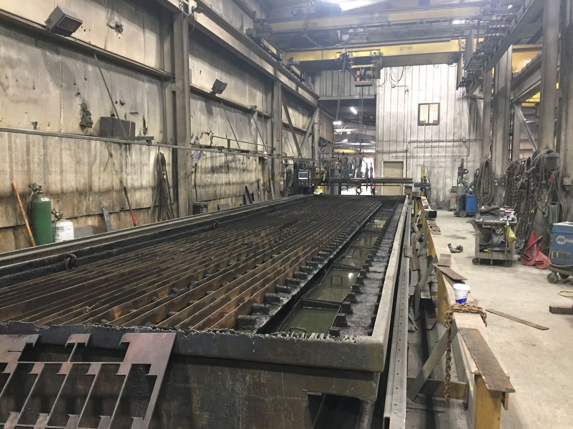 Metal cutting machine in an industrial setting, with water bed and cutting torch.