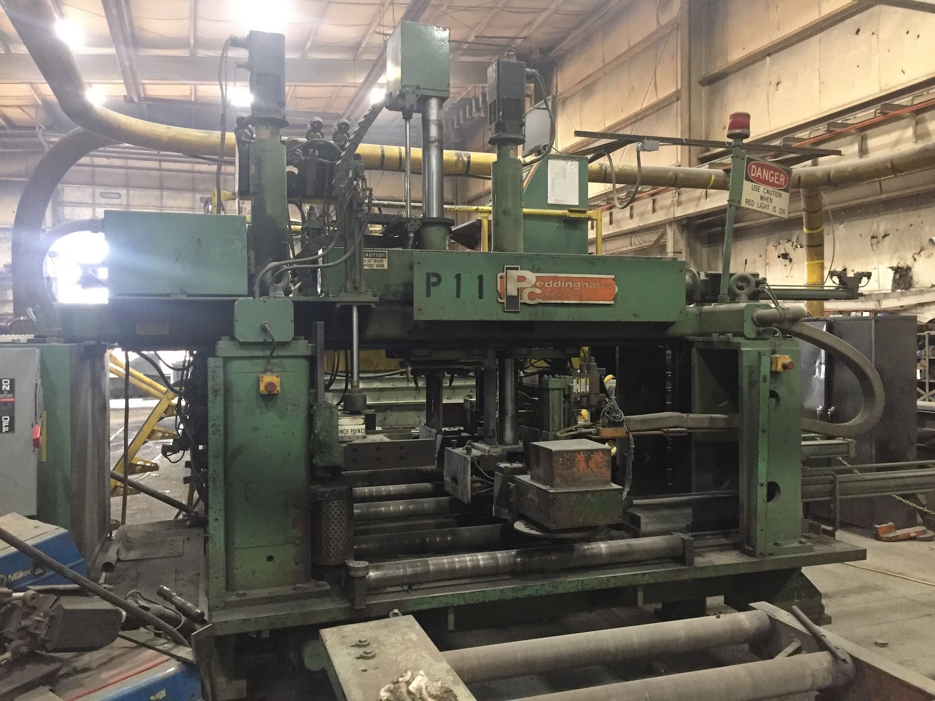Large green industrial machine labeled P11 in a factory.