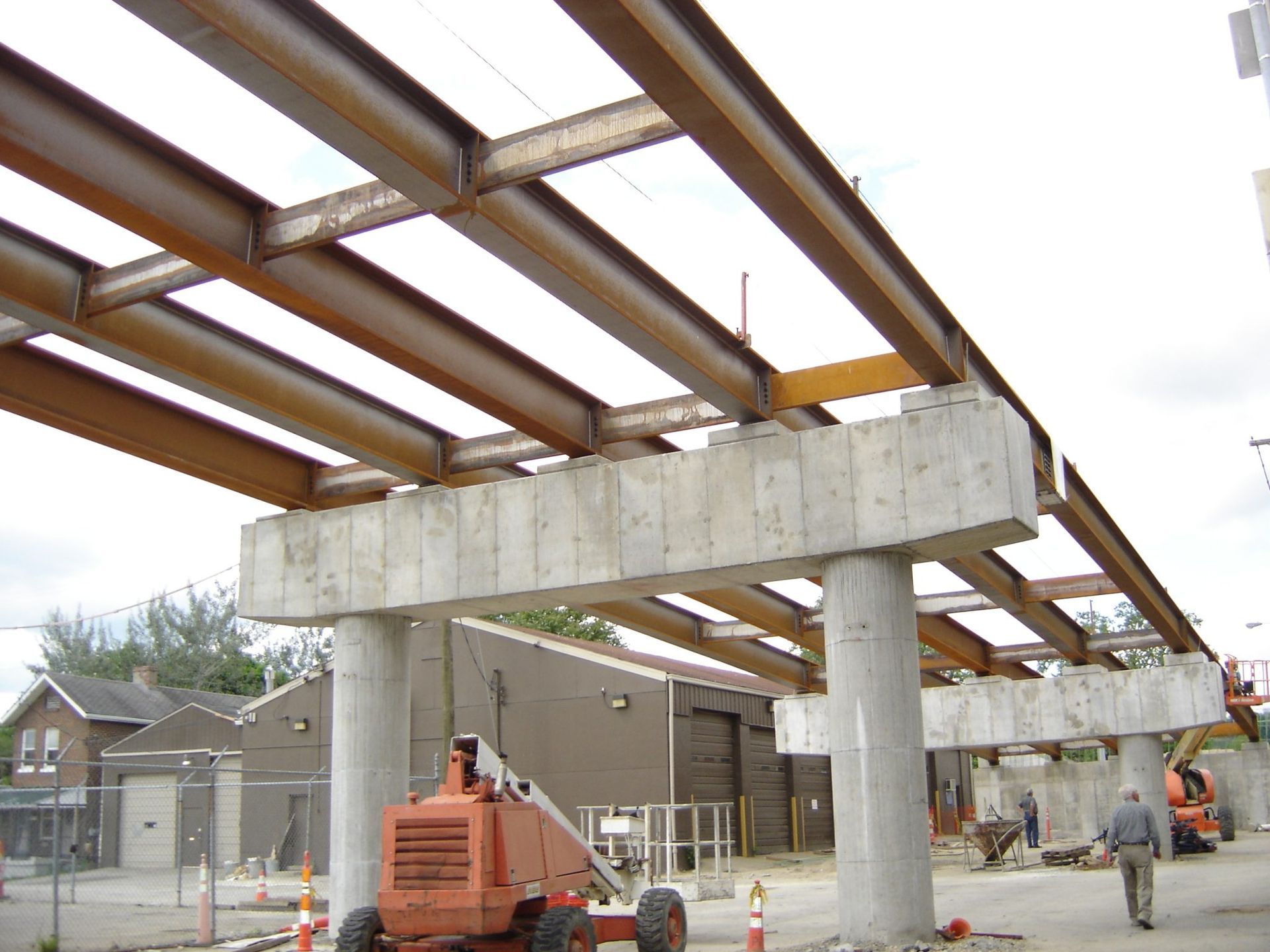 Construction site with steel beams supported by concrete pillars.
