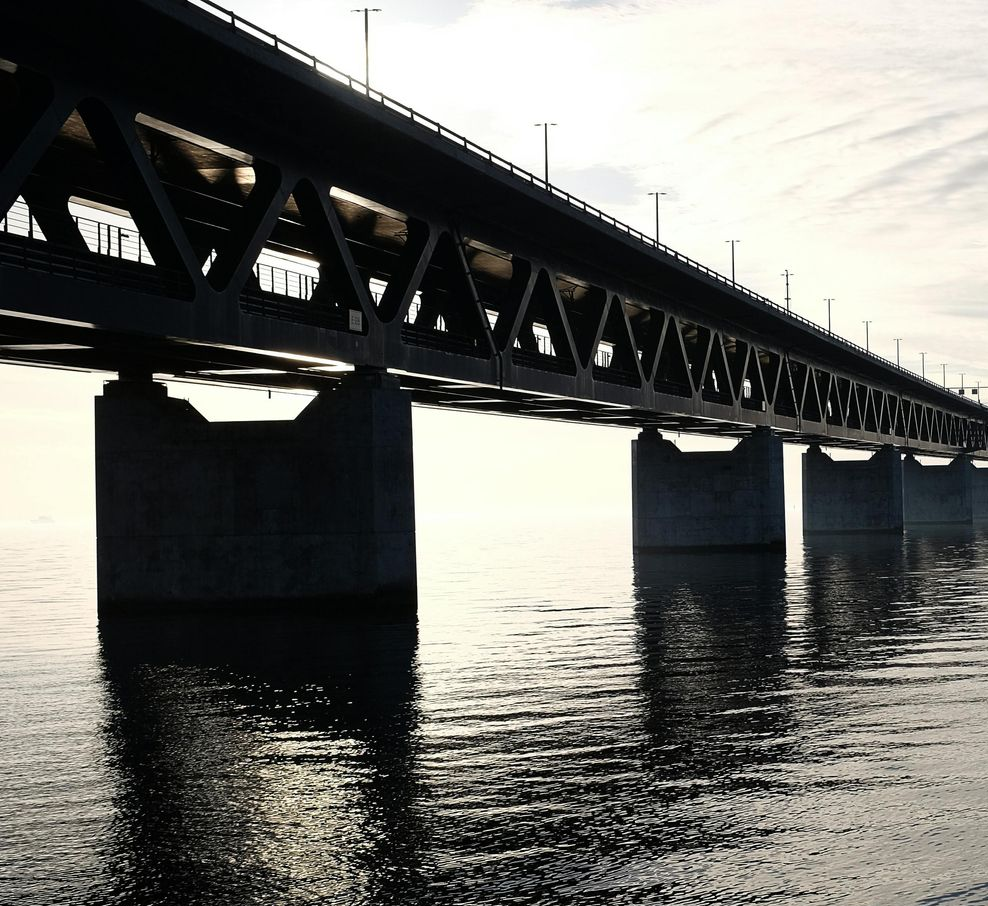 Bridge over water; dark silhouette against bright sky.