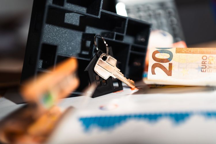 Close-up of a key in a lock with a 20 euro banknote in the background.