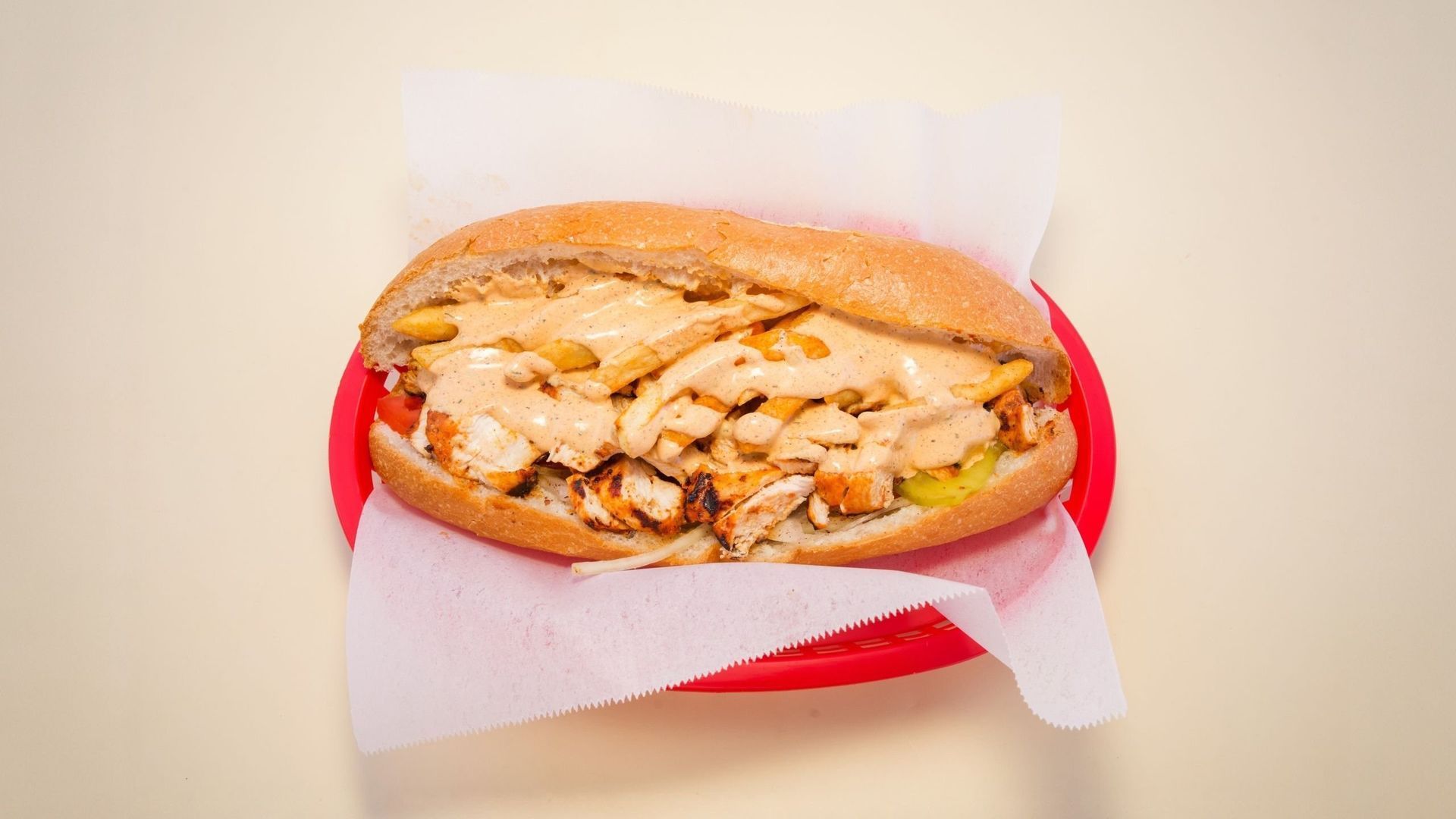 Sandwich with chicken and lettuce on red-and-white paper wrapper