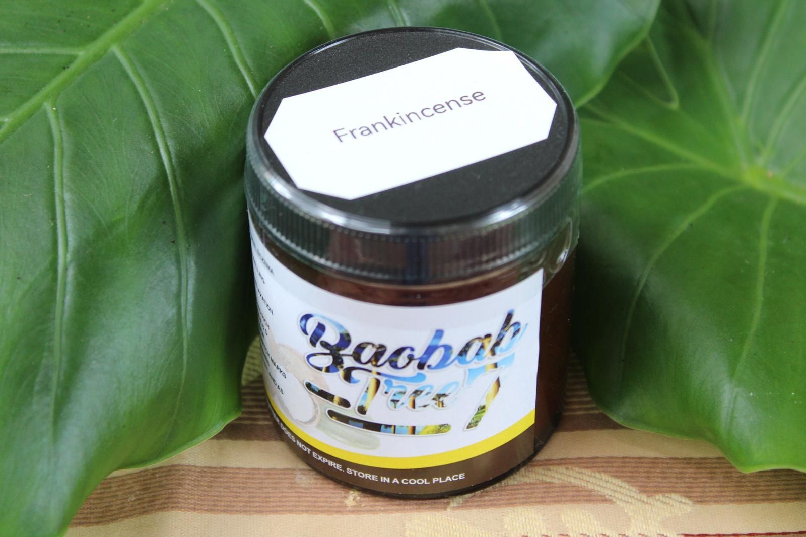 Jar of baobab butter with black lid on large green leaves