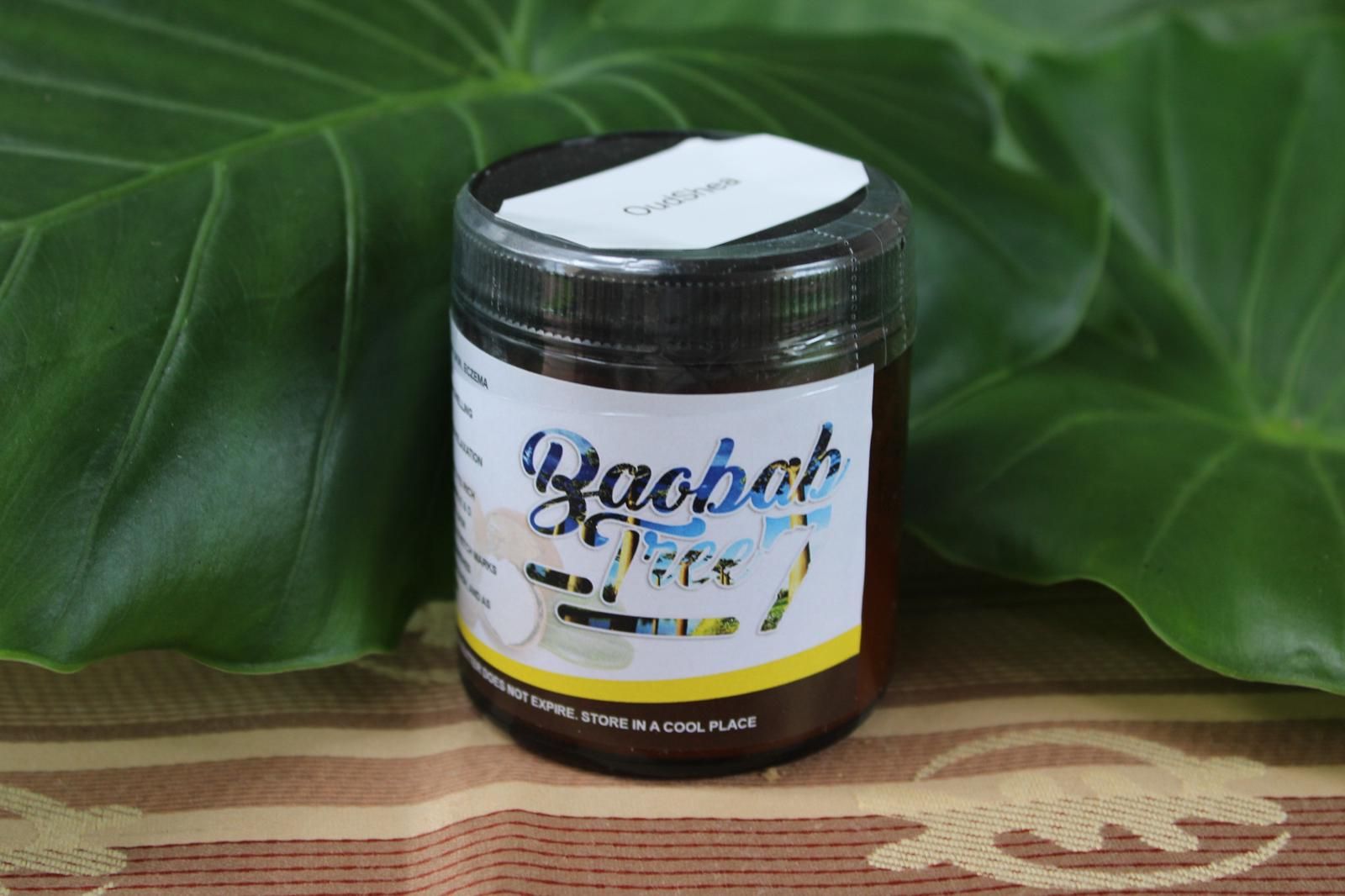 Baobab-flavored drink jar on a wooden surface with large green leaves behind it