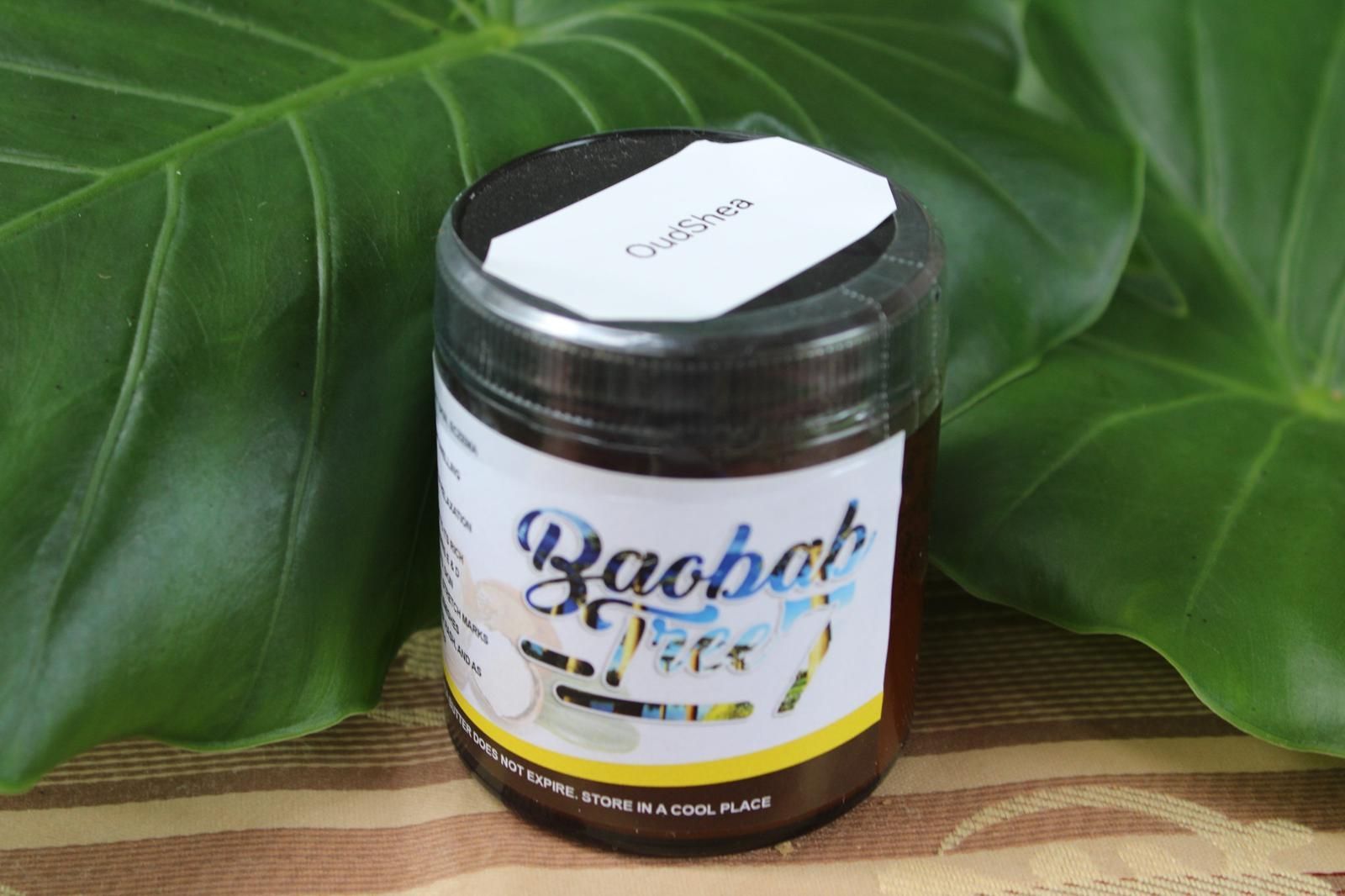 Baobab-flavored drink jar on a wooden surface with large green leaves behind it