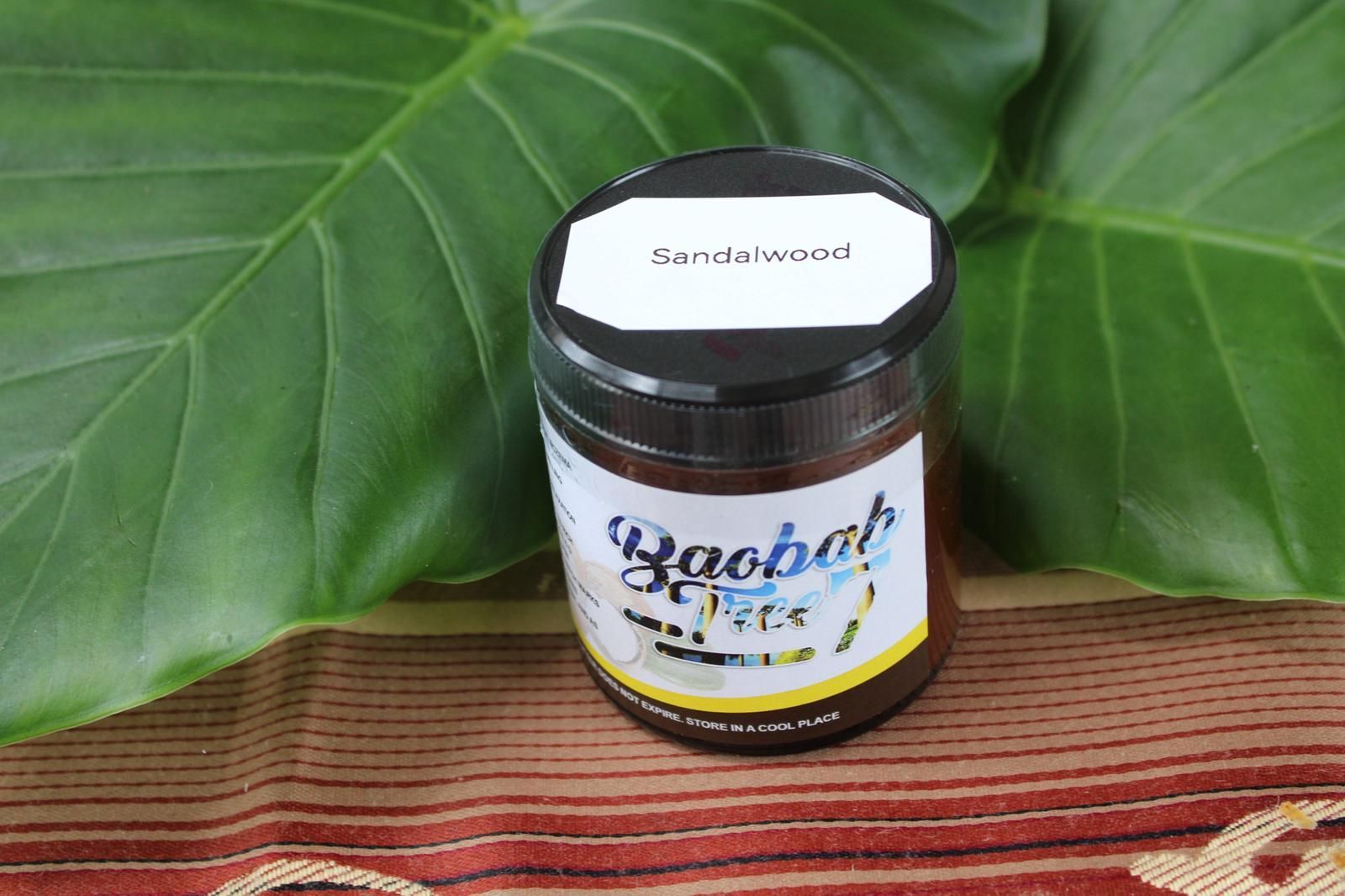 Jar of honey on a woven cloth with green leaves in the background.