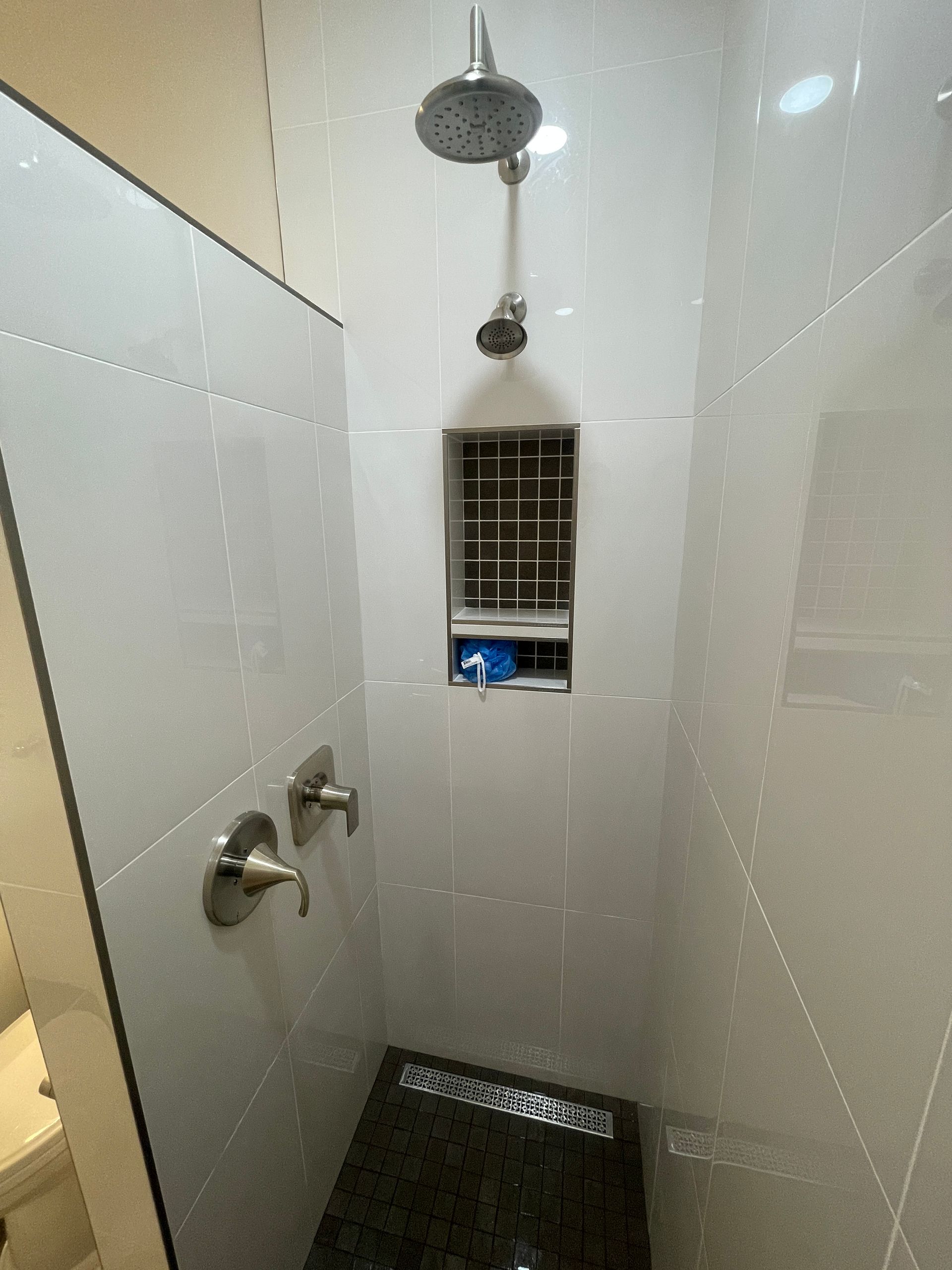 A shower with a shower head and two shower heads in a bathroom.