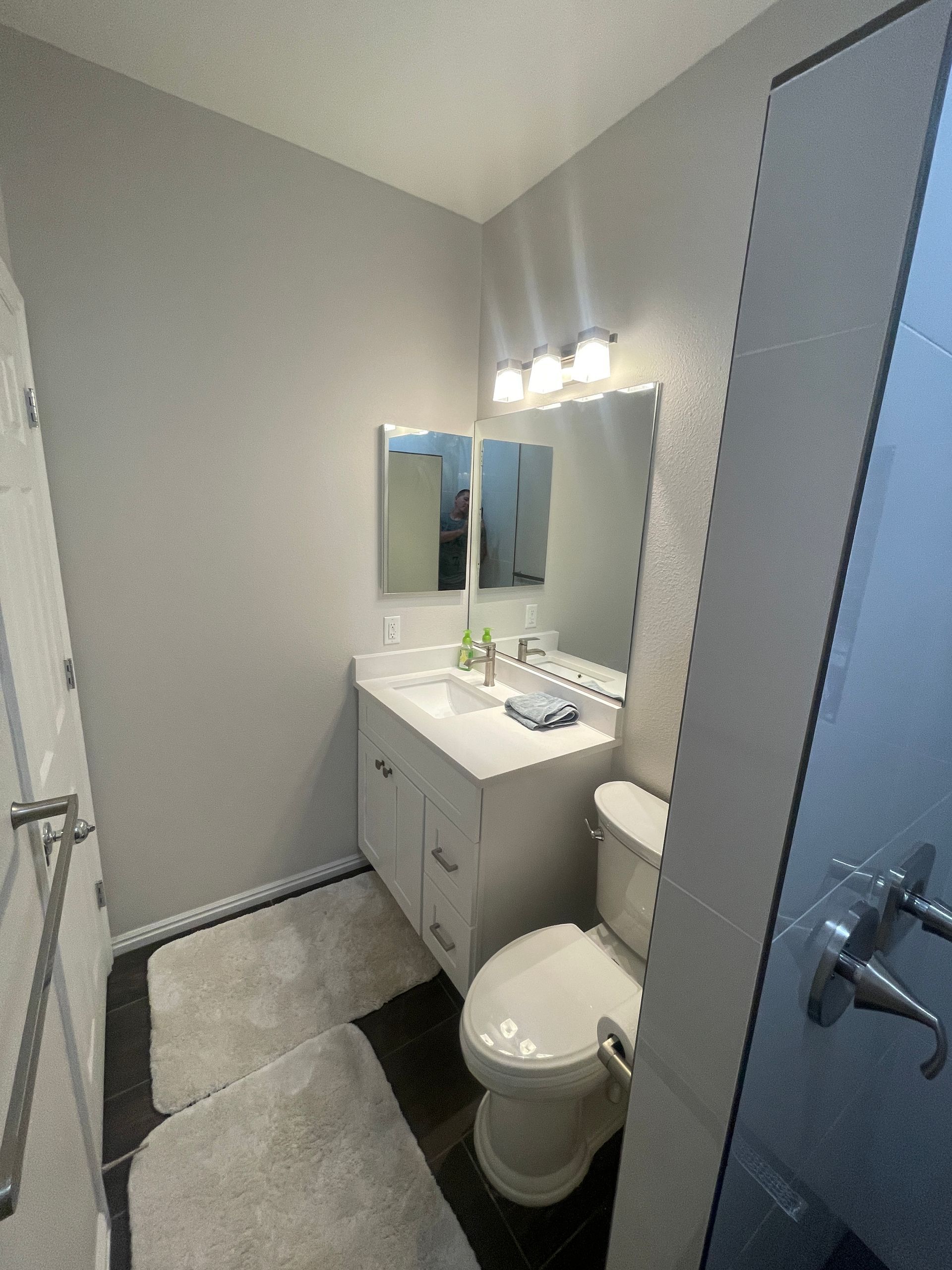 A bathroom with a toilet , sink , mirror and shower.