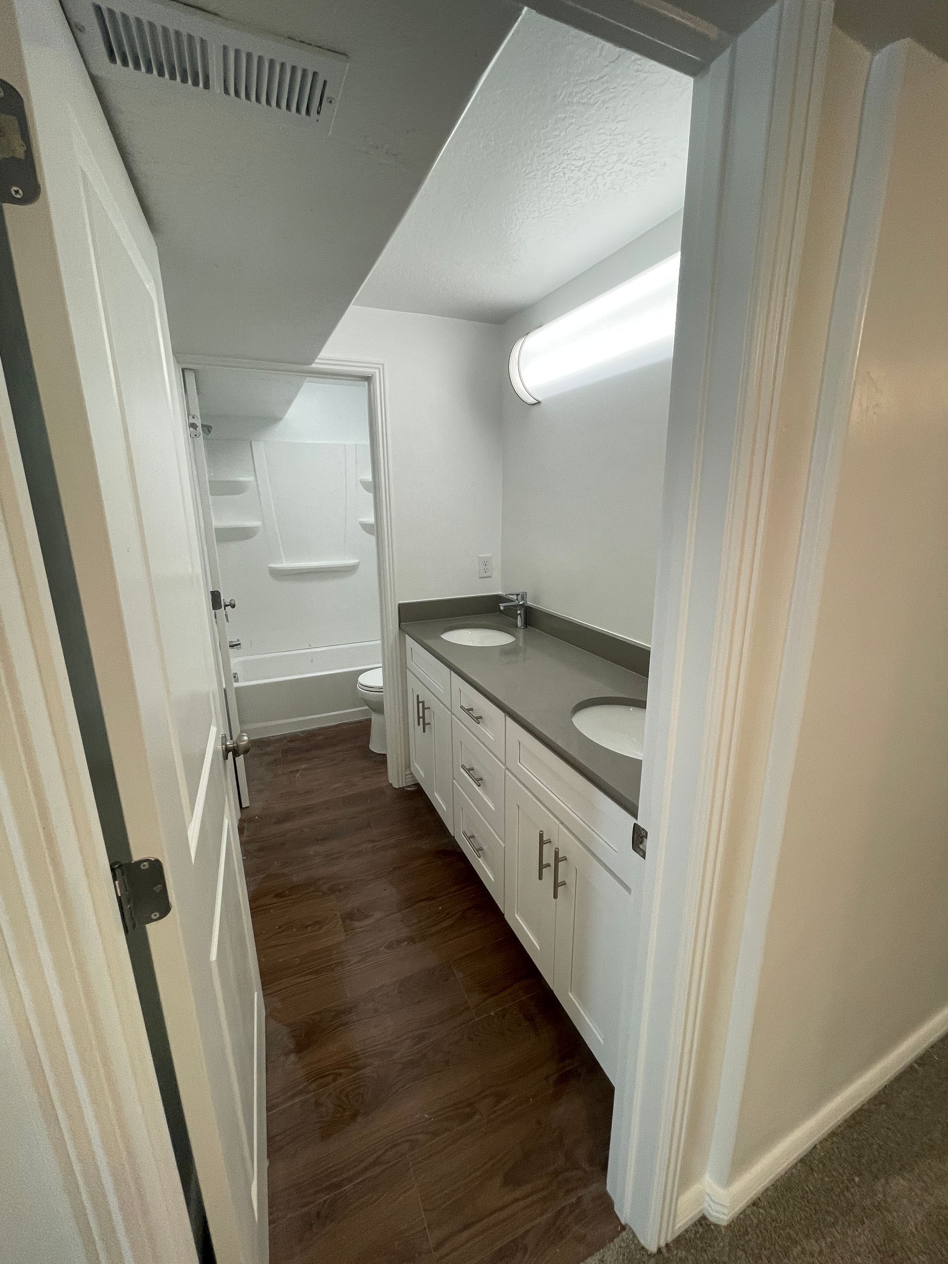 A bathroom with two sinks , a toilet , and a walk in shower.