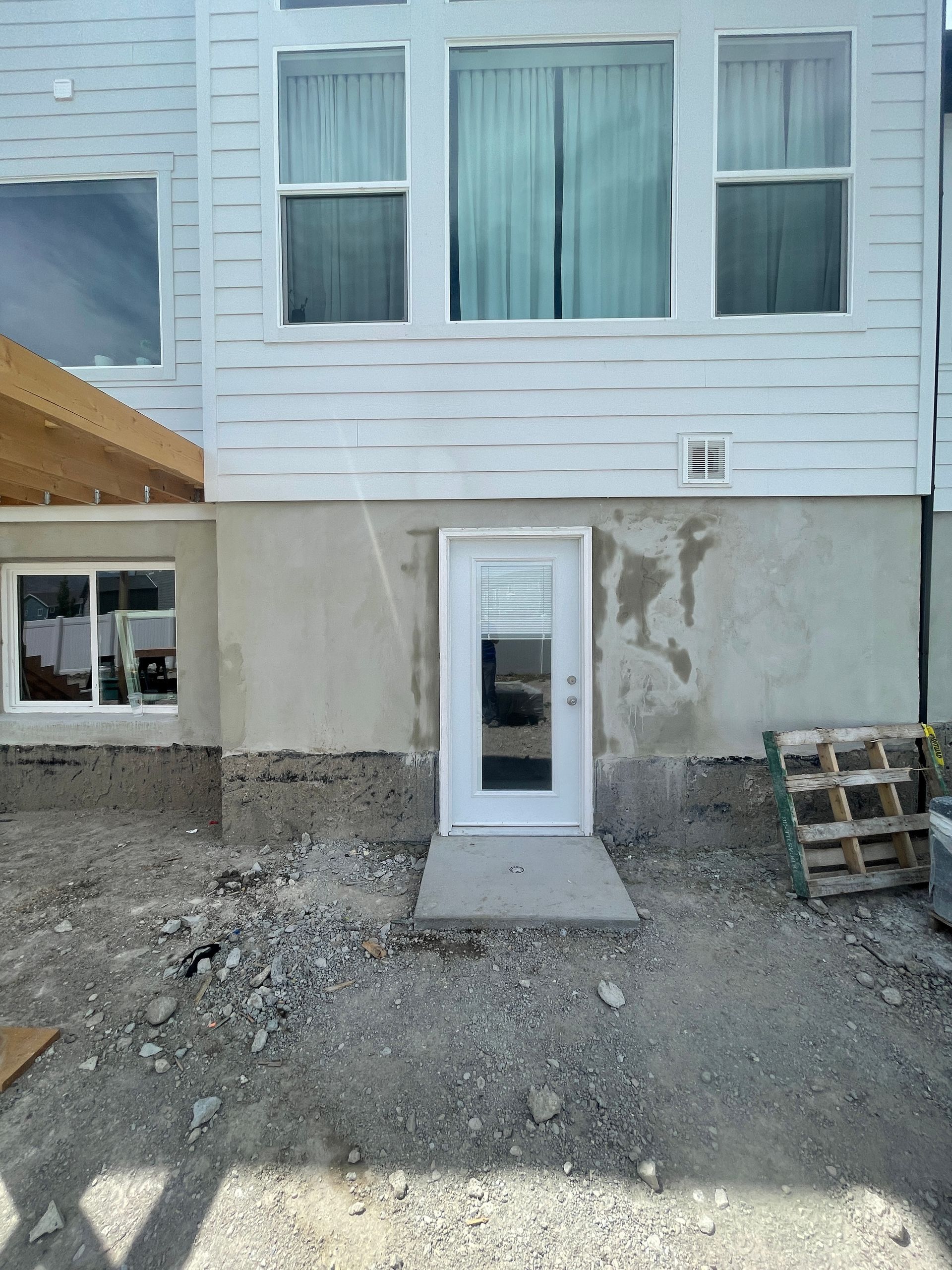A white house with a door and windows is under construction.
