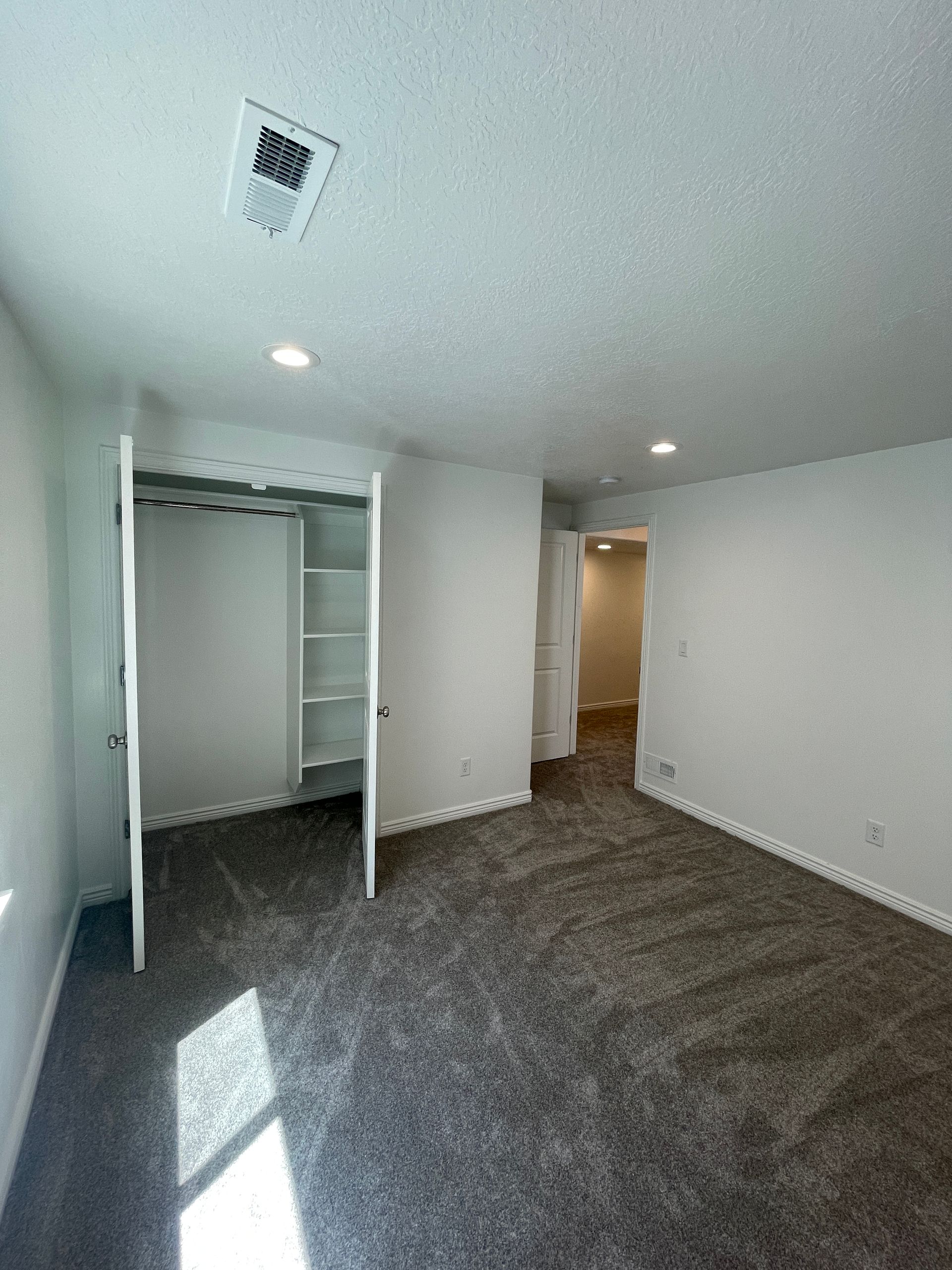 An empty bedroom with a closet and a carpeted floor.