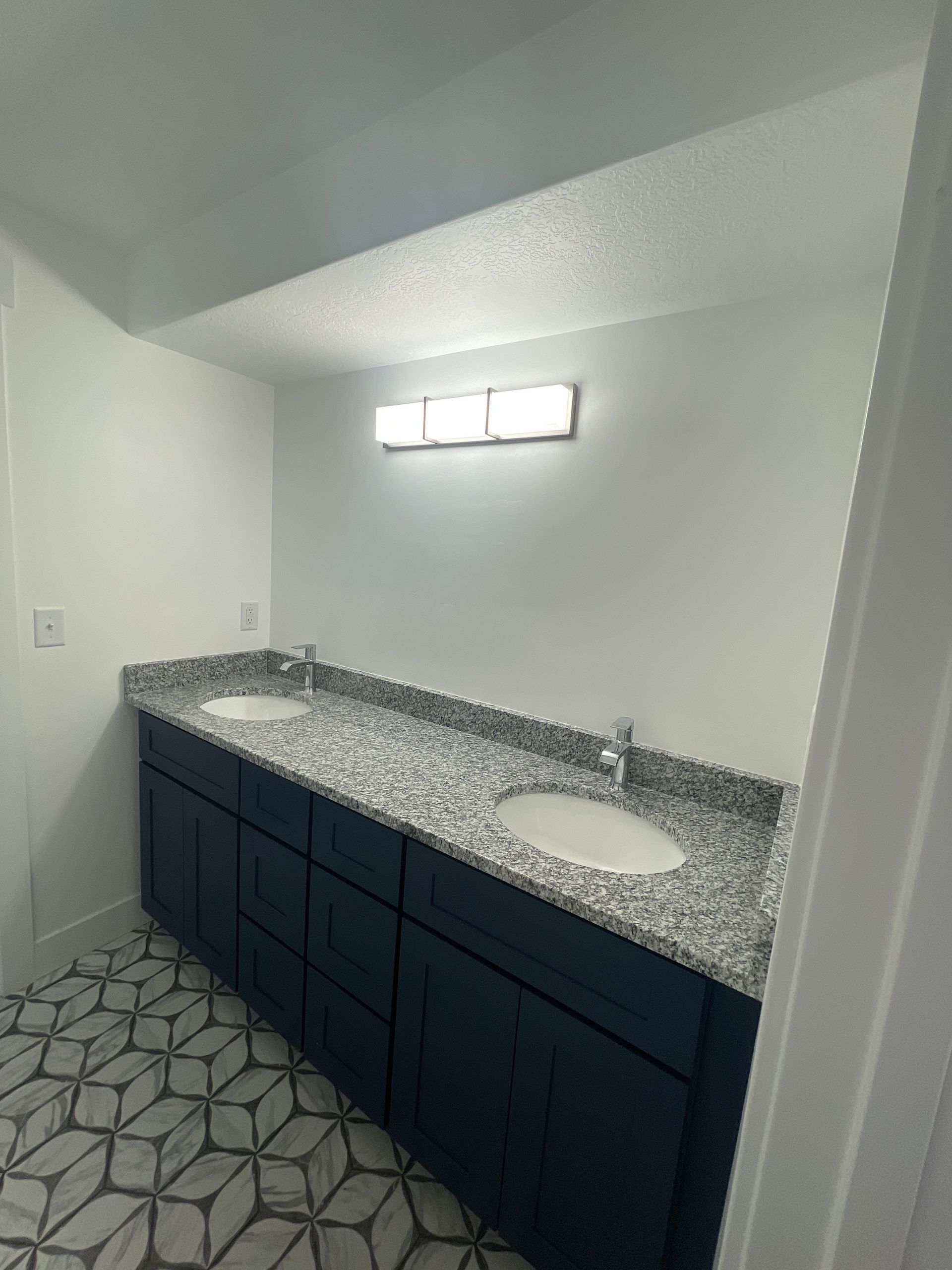 A bathroom with two sinks and blue cabinets.