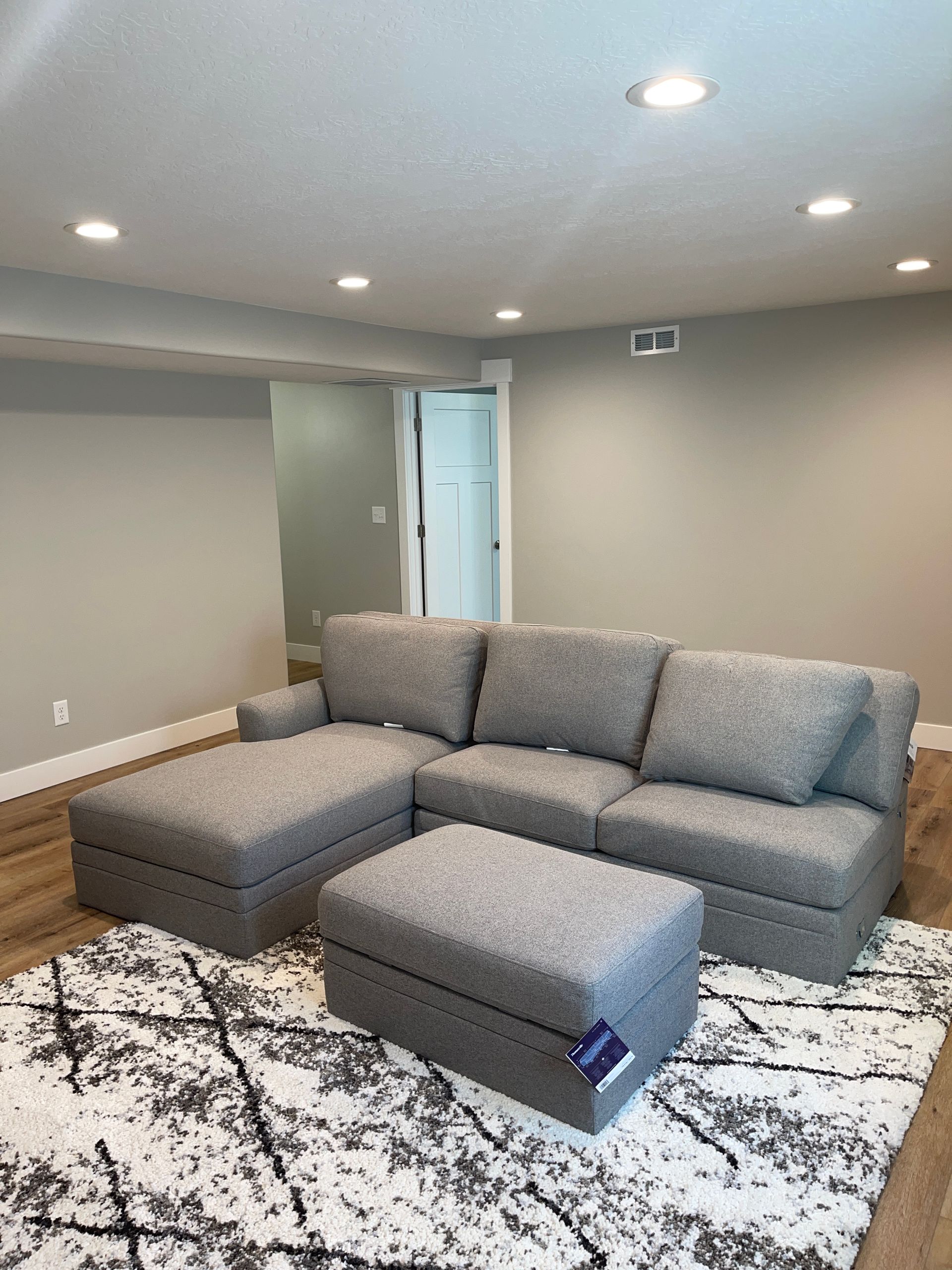 A living room with a couch , ottoman , and rug.