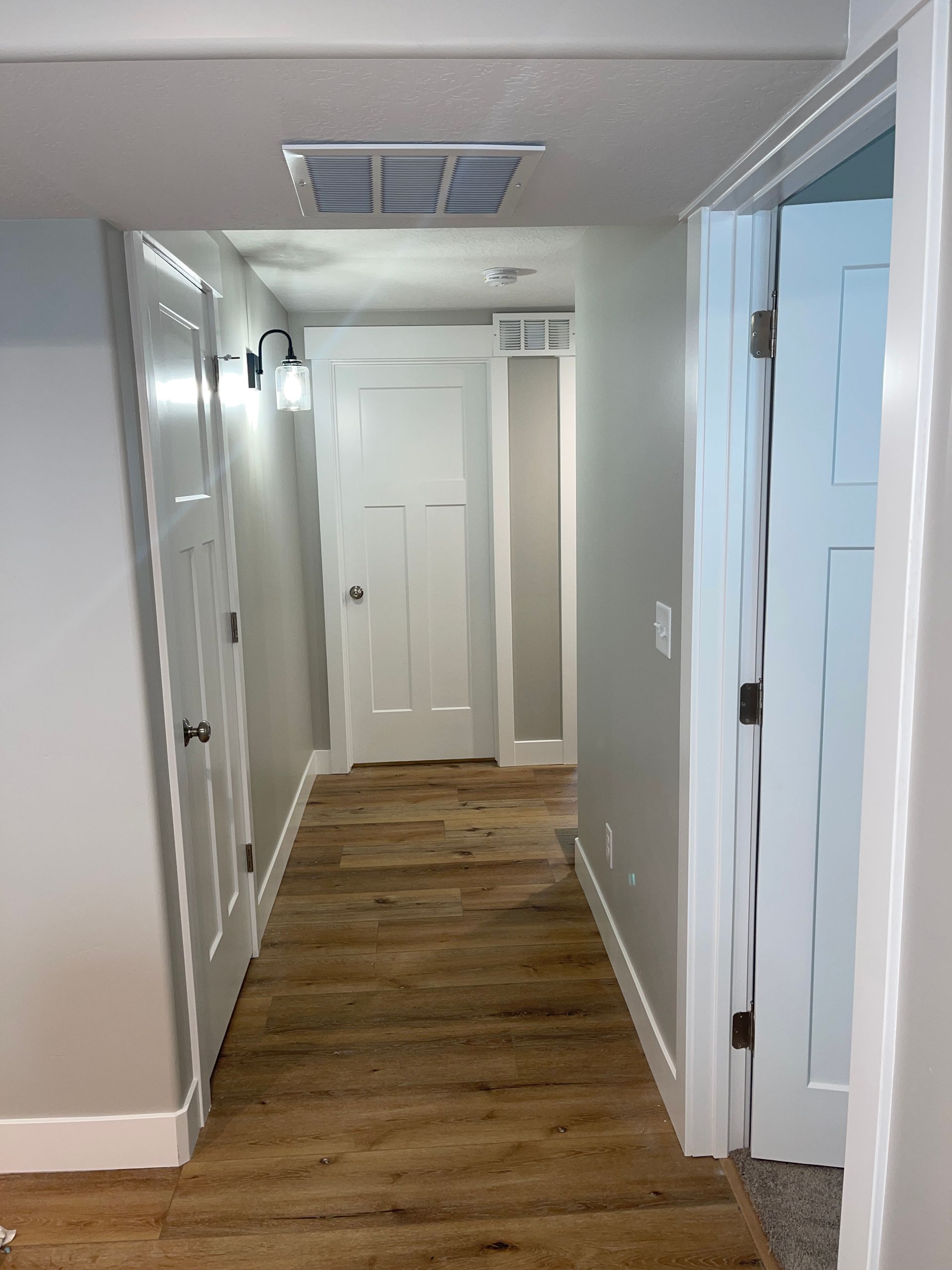 A hallway with wooden floors and white doors in a house.