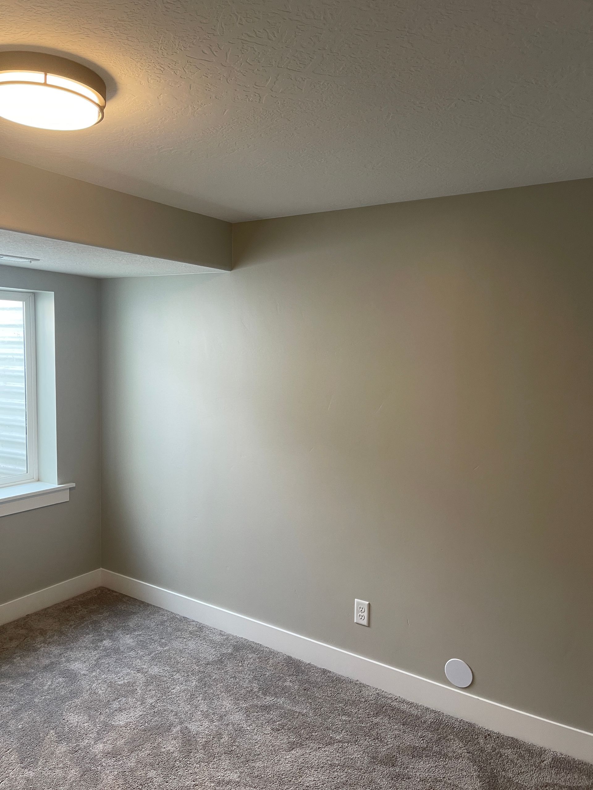 An empty room with a window and a light on the ceiling.
